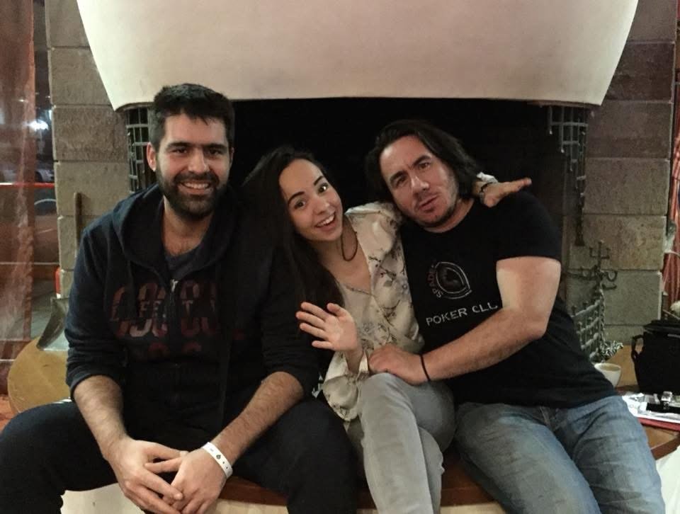 Three people sitting together in front of a fireplace, smiling and posing for the photo.