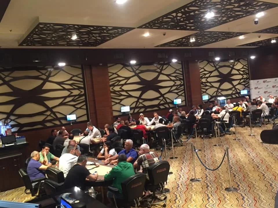People playing poker at tables in a casino or gaming room.