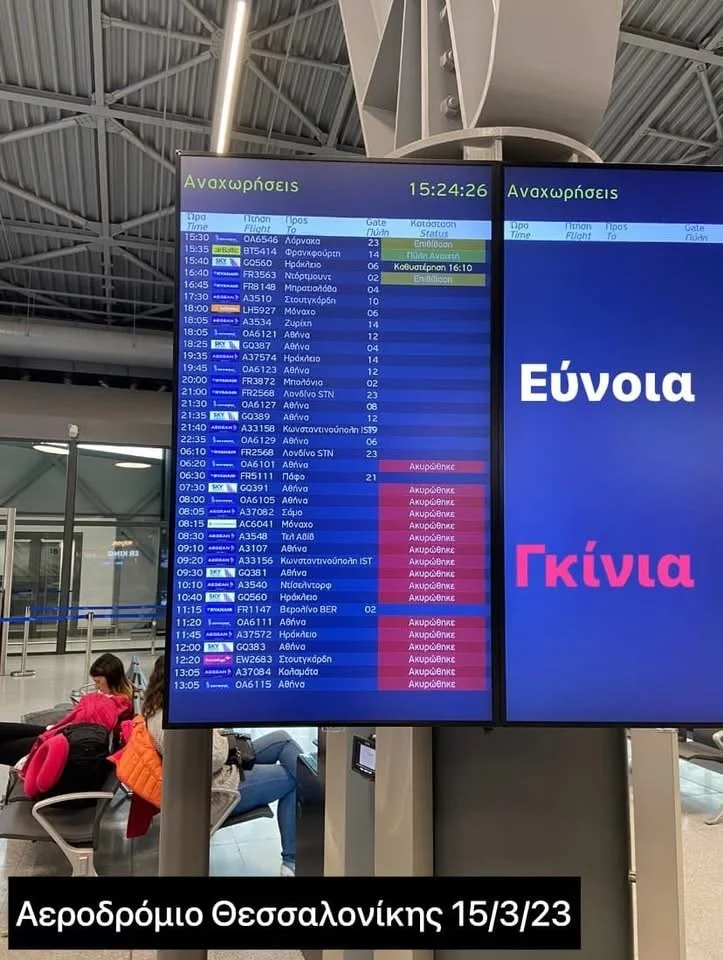 Digital flight information display at Thessaloniki Airport, showing departure flights, times, destinations, and status updates in Greek.