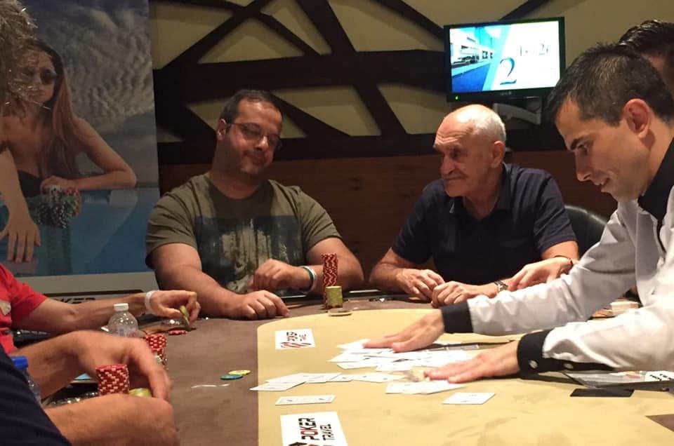 People playing poker at a casino table with stacks of chips, playing cards, and a dealer in a white shirt.