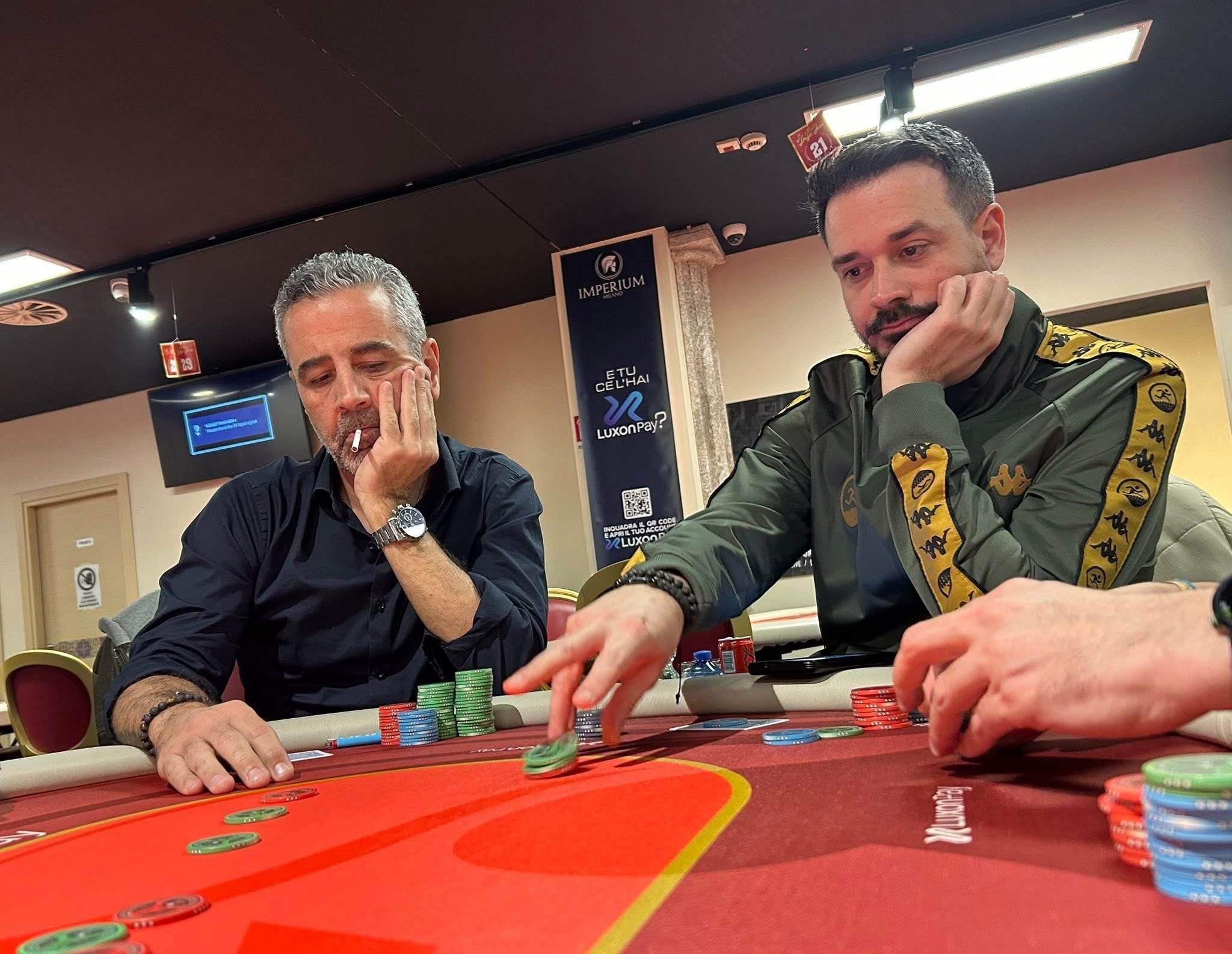 Two men poker playing at a casino table with poker chips in front of them.