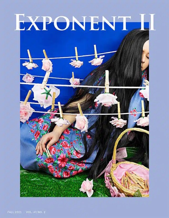 Cover of a magazine titled 'Exponent II' with a woman wearing a traditional dress, sitting on grass, surrounded by hanging pink flowers on lines, a wicker basket filled with wooden sticks, and a blue background.