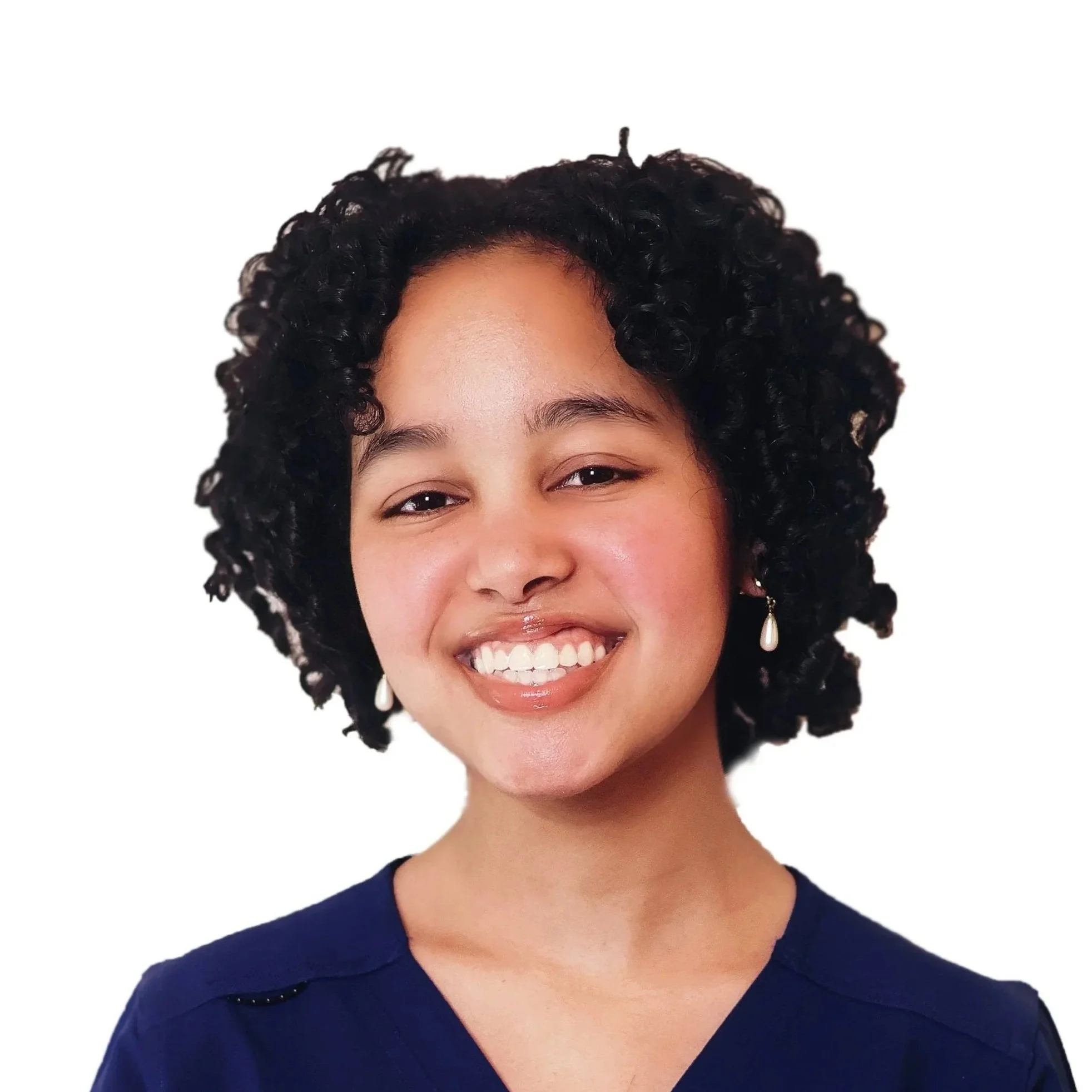 Close-up of a woman with dark curly hair, smiling with visible teeth, wearing pearl earrings and a navy blouse, against a white background.