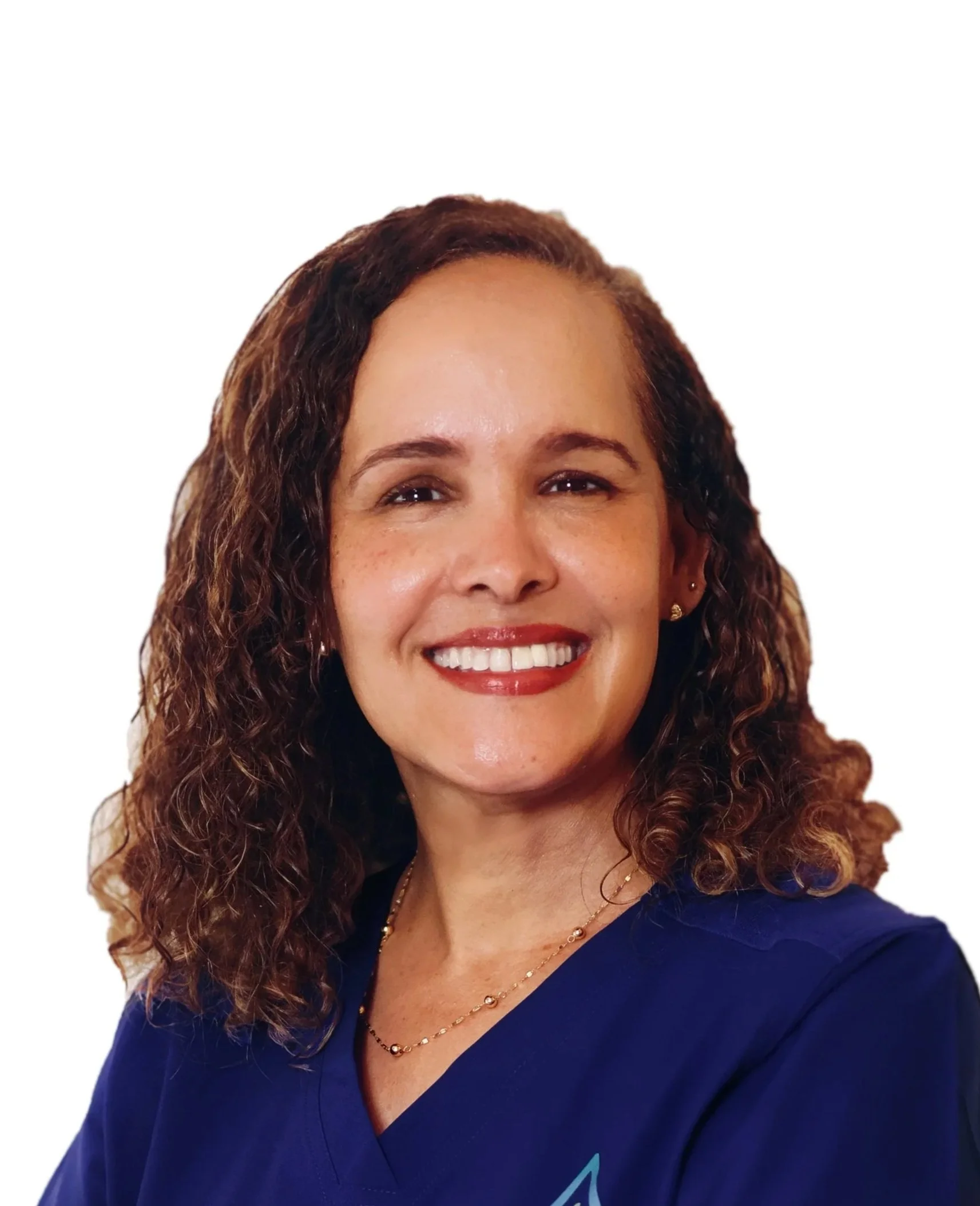 A woman with curly brown hair, wearing a blue shirt and gold jewelry, smiling in front of a white background.