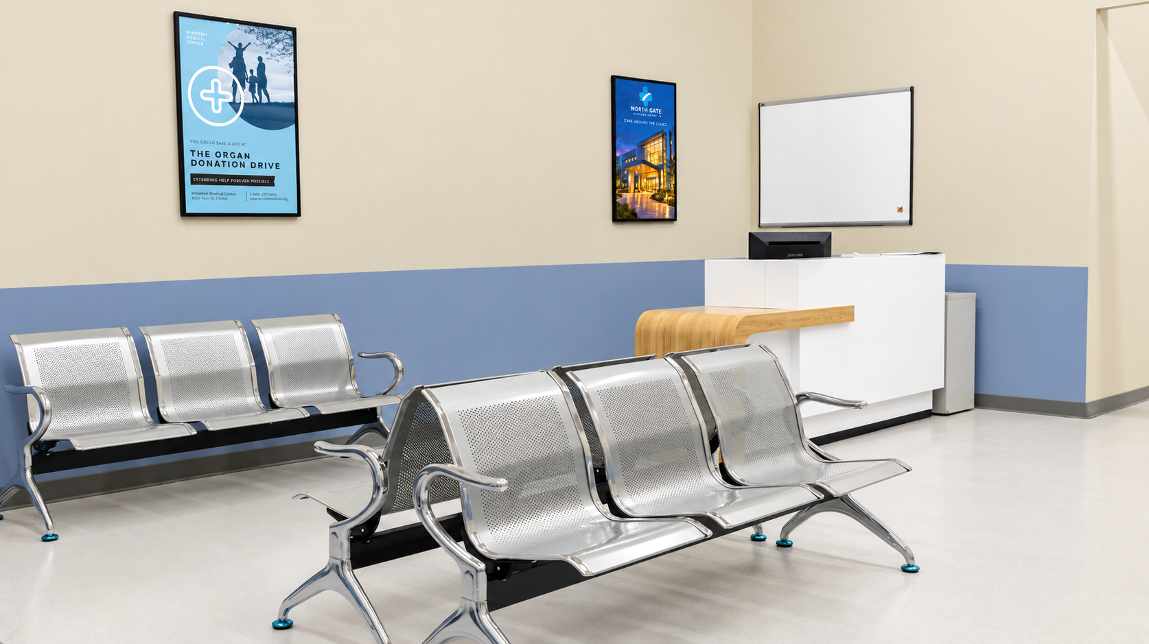 Empty waiting room with metal chairs, a reception desk, a computer, a whiteboard, and framed posters on the wall.
