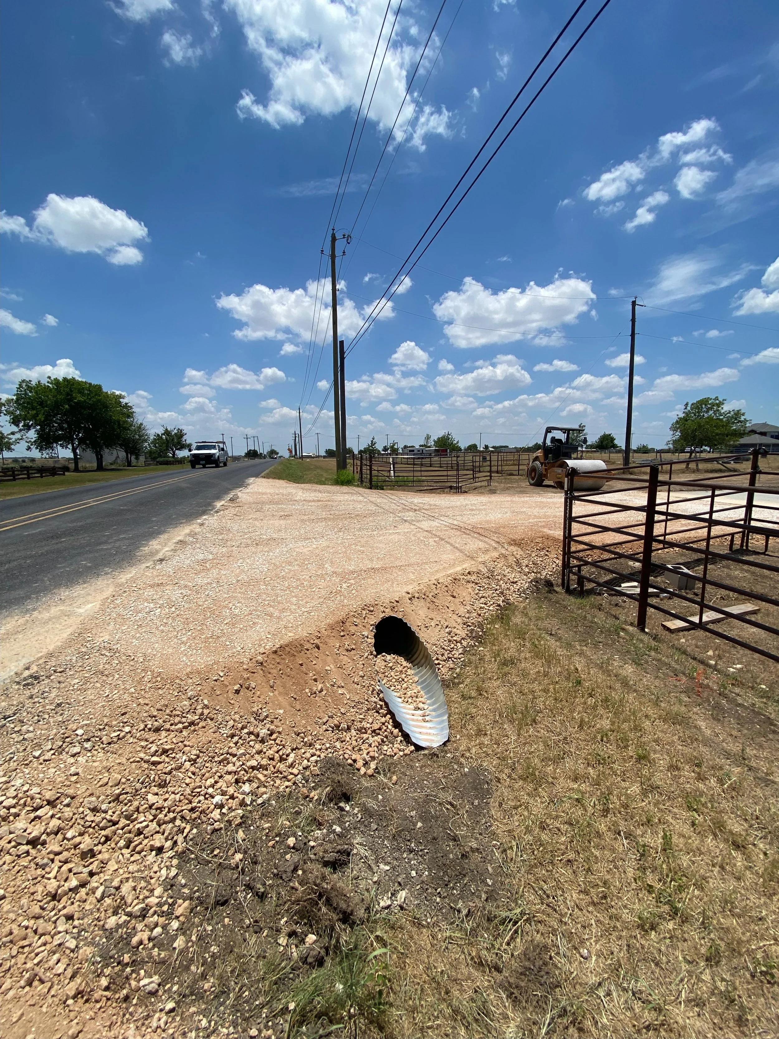 JR Excavating compactor roller grading and compacting a rural road in Georgetown, Texas.