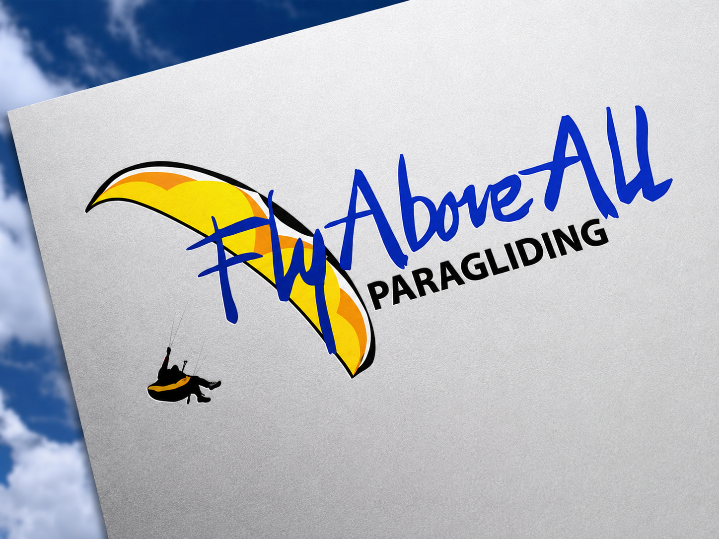 A sign for FlyAboveAll Paragliding features a stylized yellow and orange paraglider with a person flying underneath.