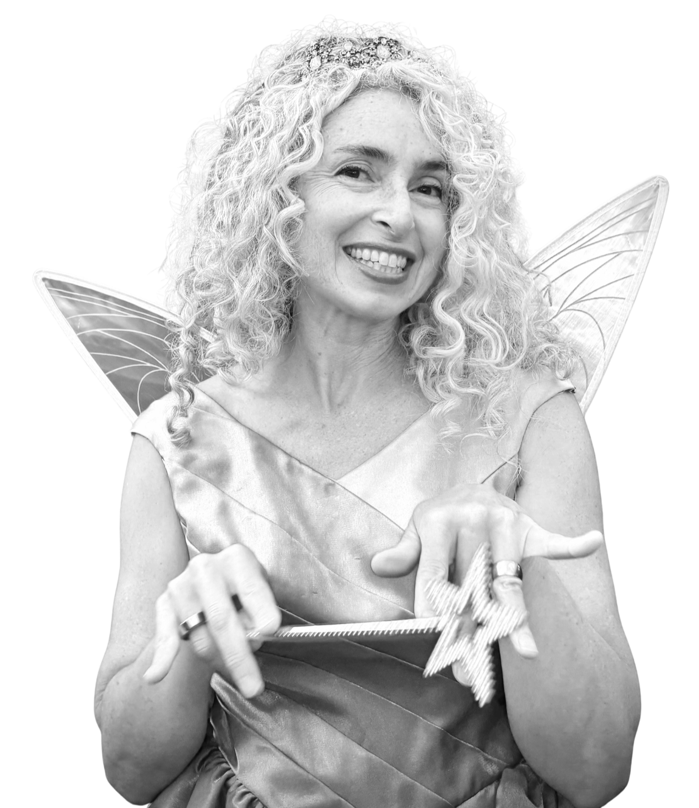 A woman with curly hair dressed as a fairy, wearing wings and a dress, holding a wrapped gift with a bow.