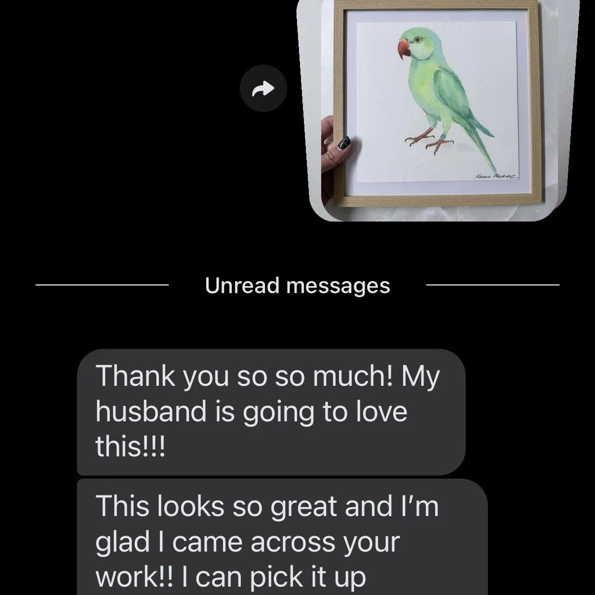 A framed watercolor illustration of a parrot with green and yellow feathers, an orange beak, and brown feet, held by a hand with painted nails.