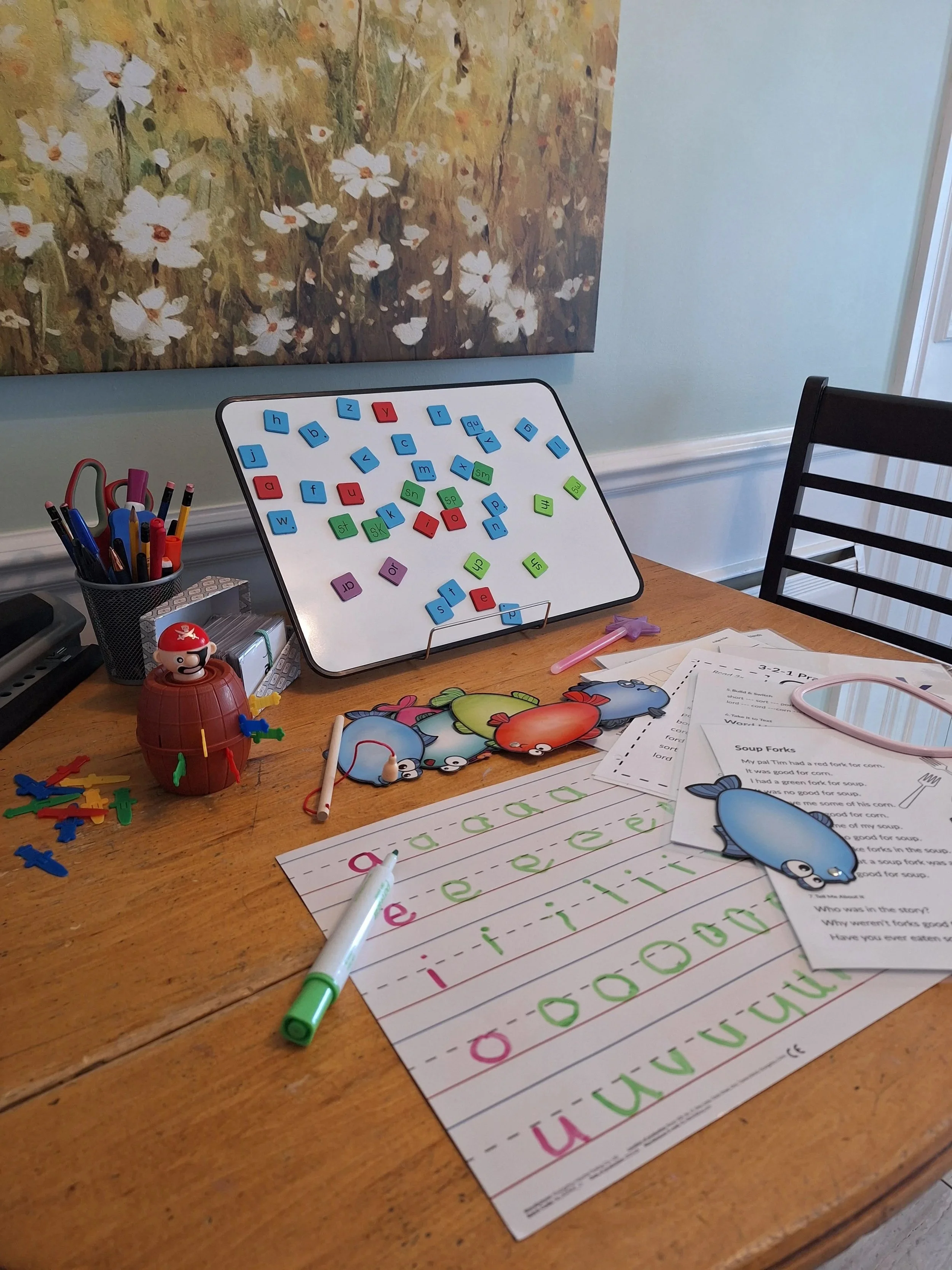 Literacy lesson set up on desk with games and worksheets.