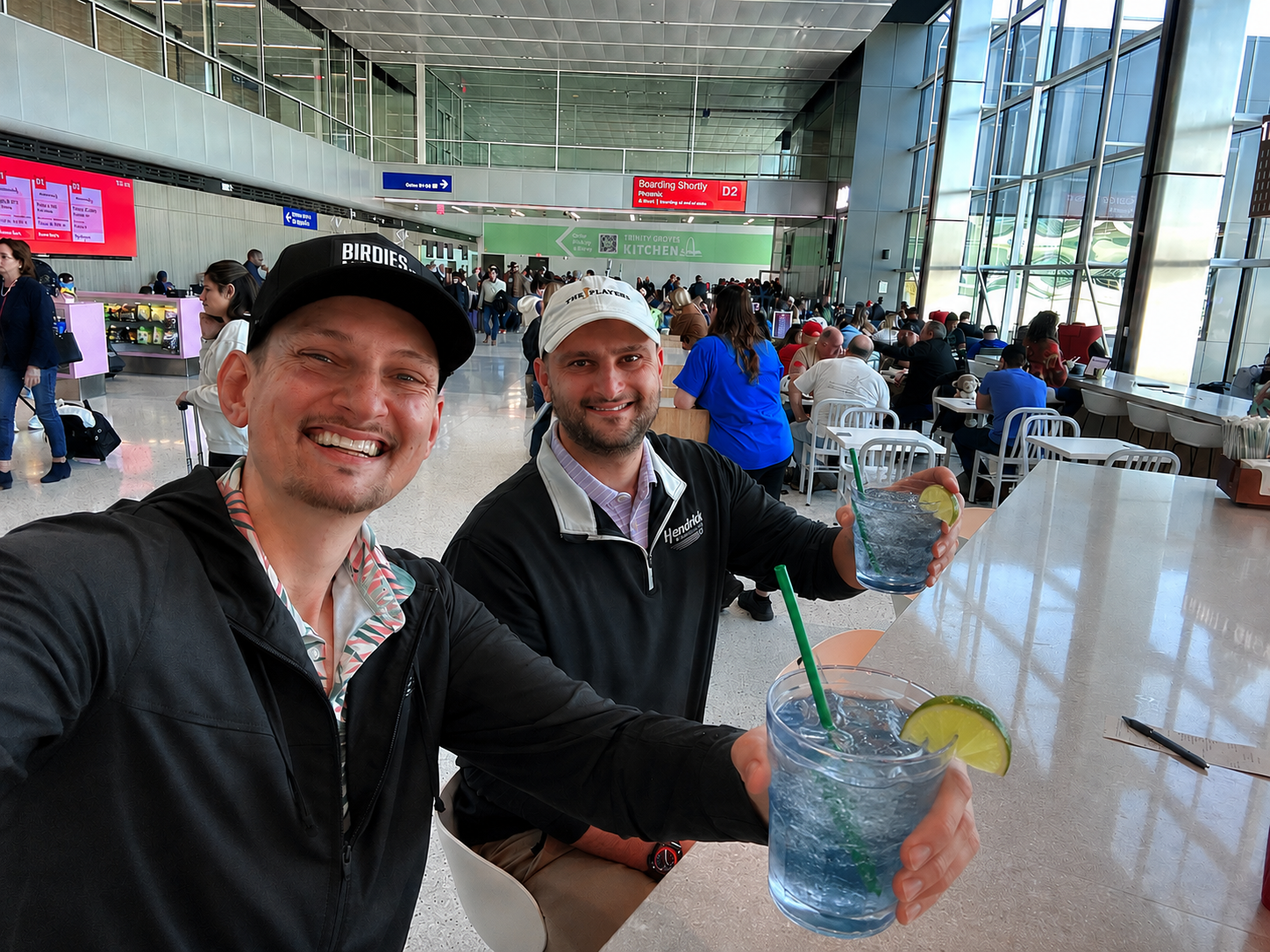 Founders of Fairway Freedom, Austin and Chance, sitting at an airport before playing golf holding water hazards to drink.