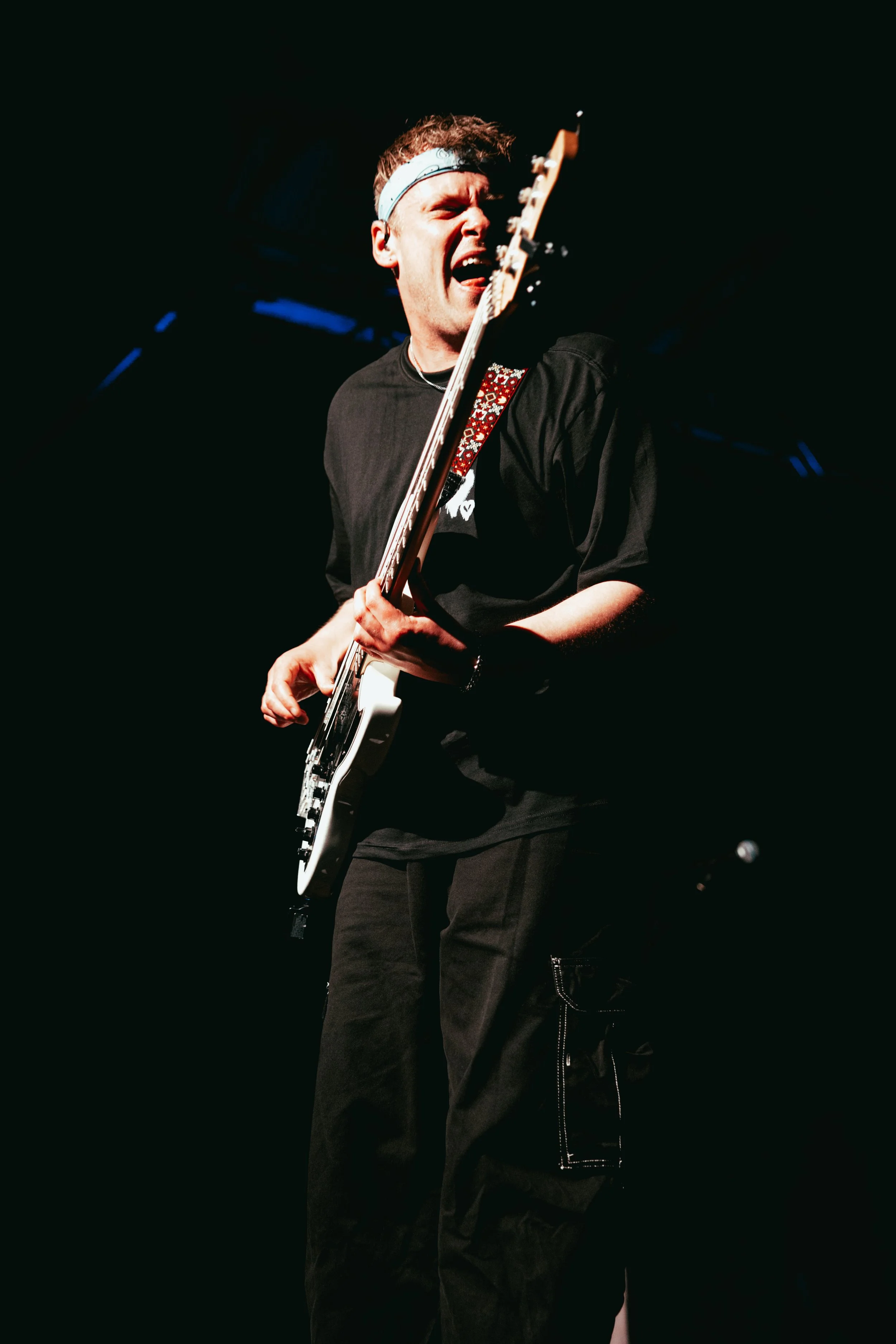 A musician playing an electric guitar with a black background.