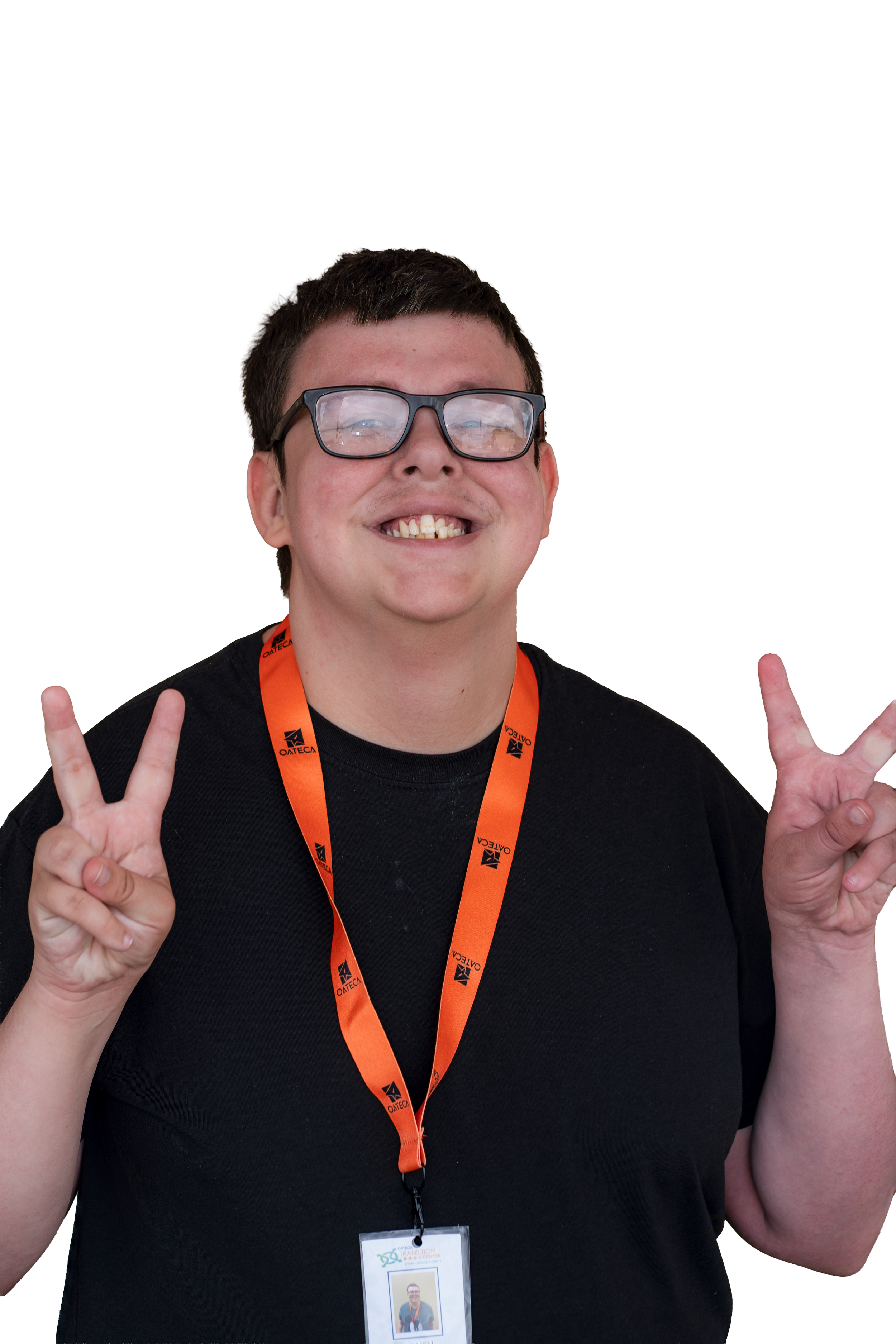 A smiling person with glasses making peace signs with both hands, wearing a black shirt and an orange lanyard with a name badge, standing in front of a presentation screen.