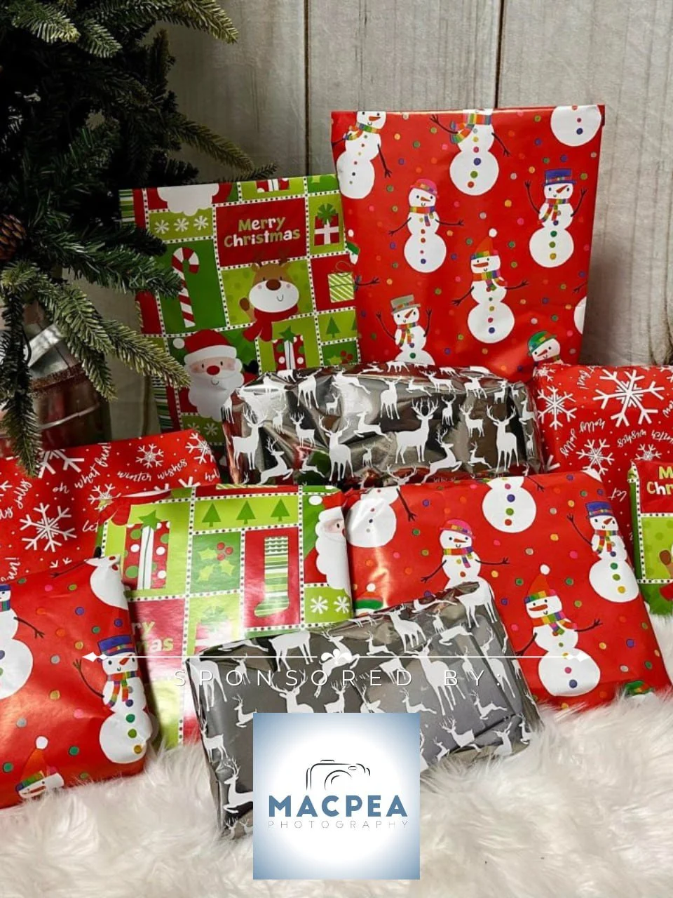 A collection of wrapped Christmas presents with holiday-themed paper, including snowmen, reindeer, Santa, and Christmas patterns, placed on a white furry surface beneath a Christmas tree.