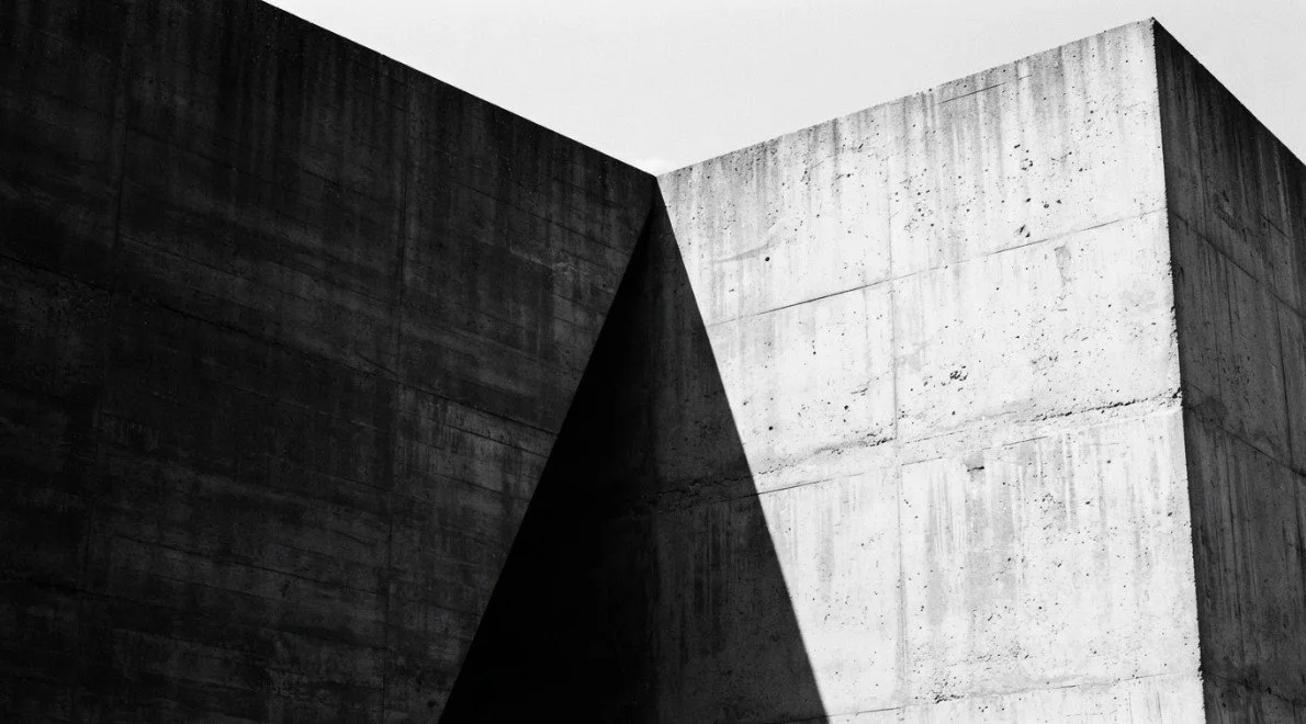 Black and white photograph of a concrete building with sharp angles and shadows.