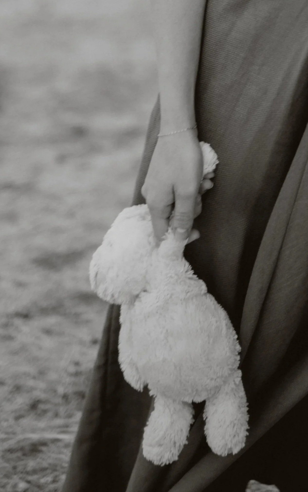 A person wearing a dark coat and a white fluffy glove holding hands with a dog with a white, fluffy tail.