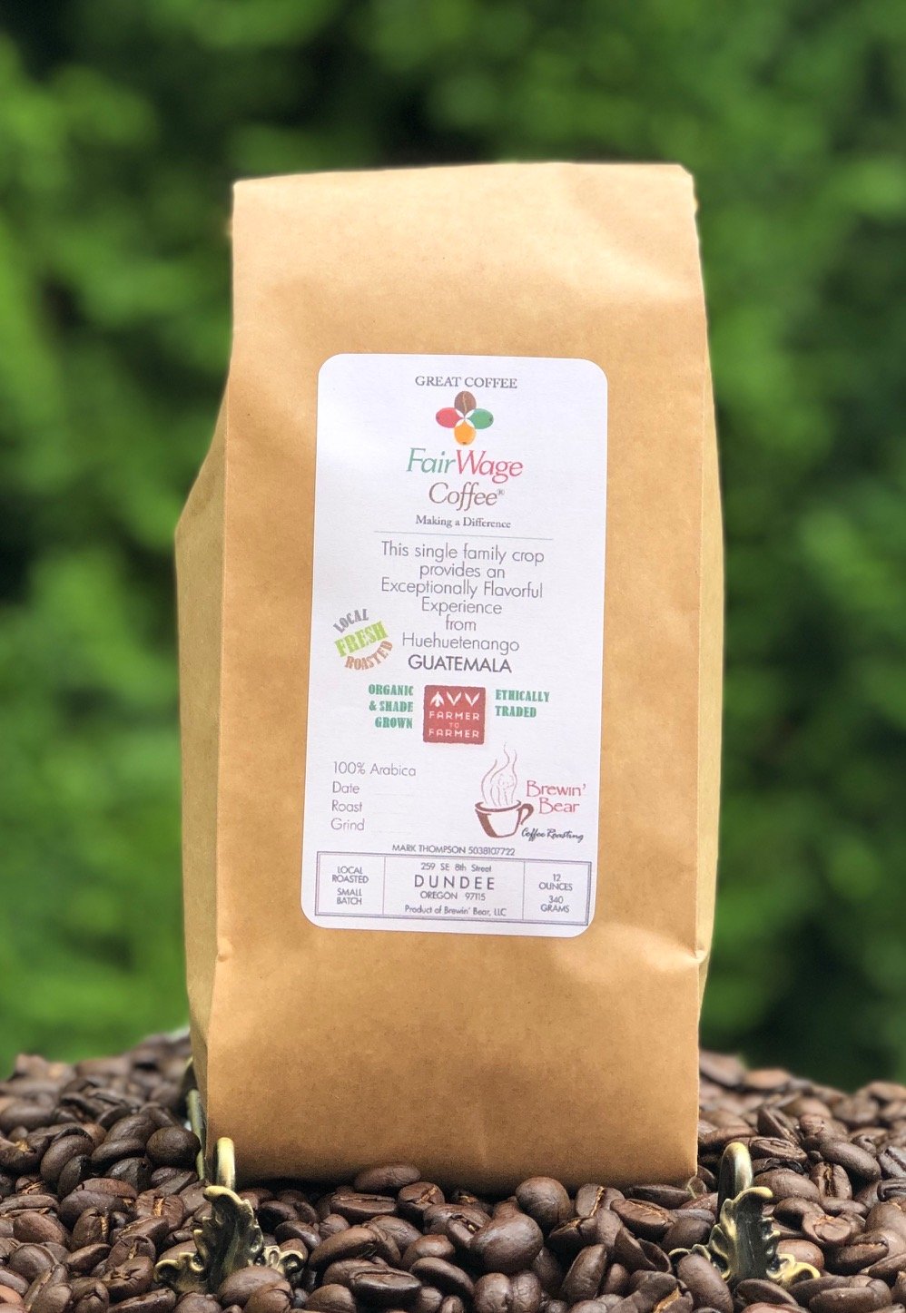 Brewin Bear coffee bag labeled from Guatemala, organic, shade-grown, and ethically traded, with a green, red, and yellow logo, positioned on coffee beans with a blurred green background.
