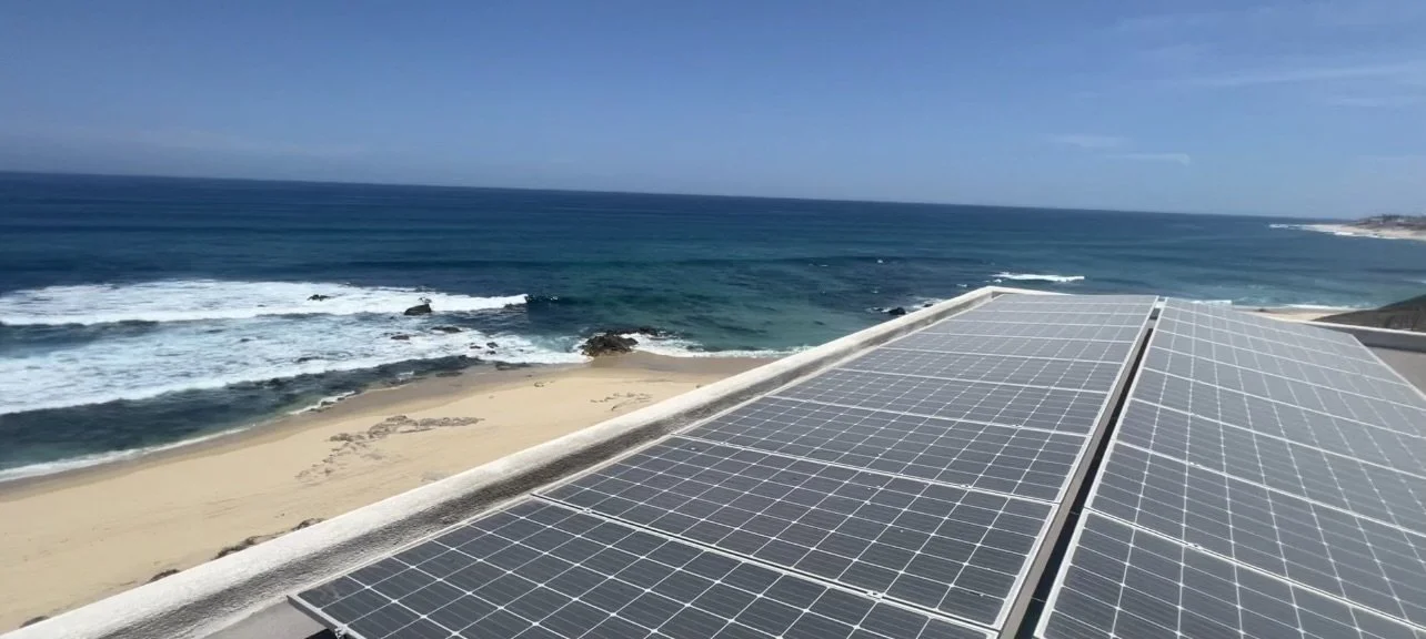 Solar panels on a rooftop overlooking a beach and ocean.