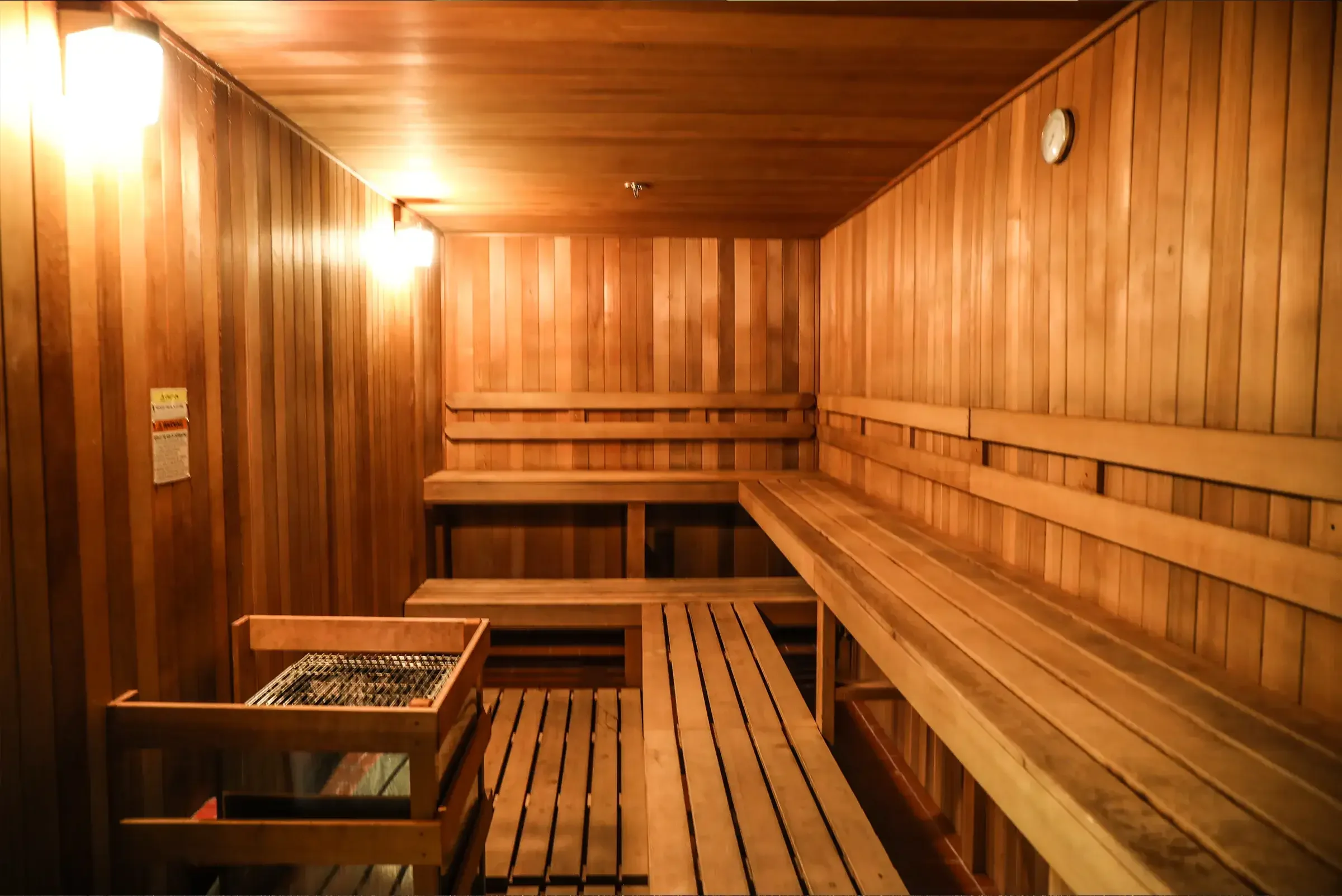 Interior view of a traditional wooden sauna with multiple benches and lighting fixtures.