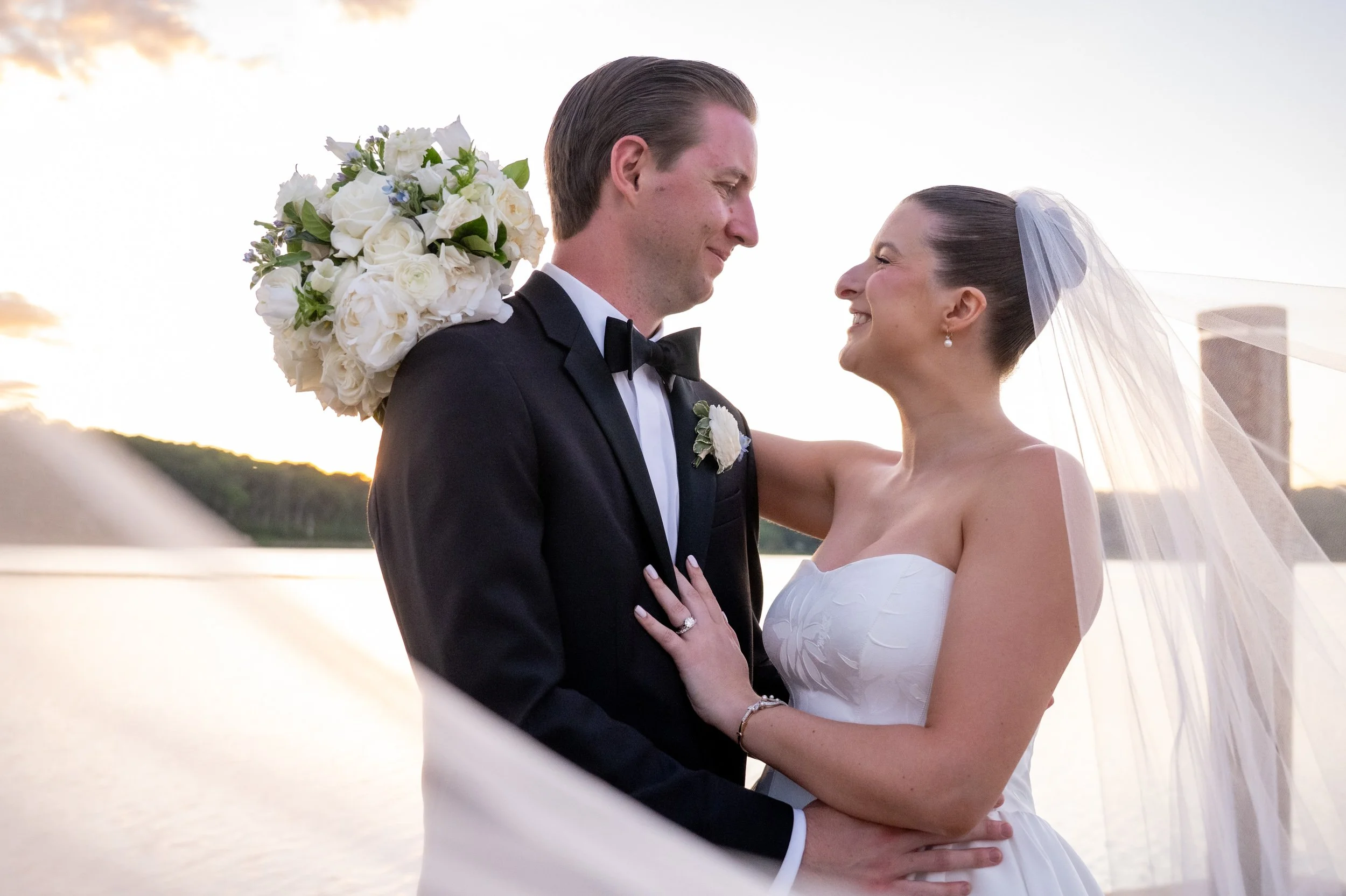 Bride and groom sharing a romantic moment under a floating wedding veil along the Mystic River waterfront at Delamar Mystic in Connecticut. Photographed by Allison Mott of Mott Collective.