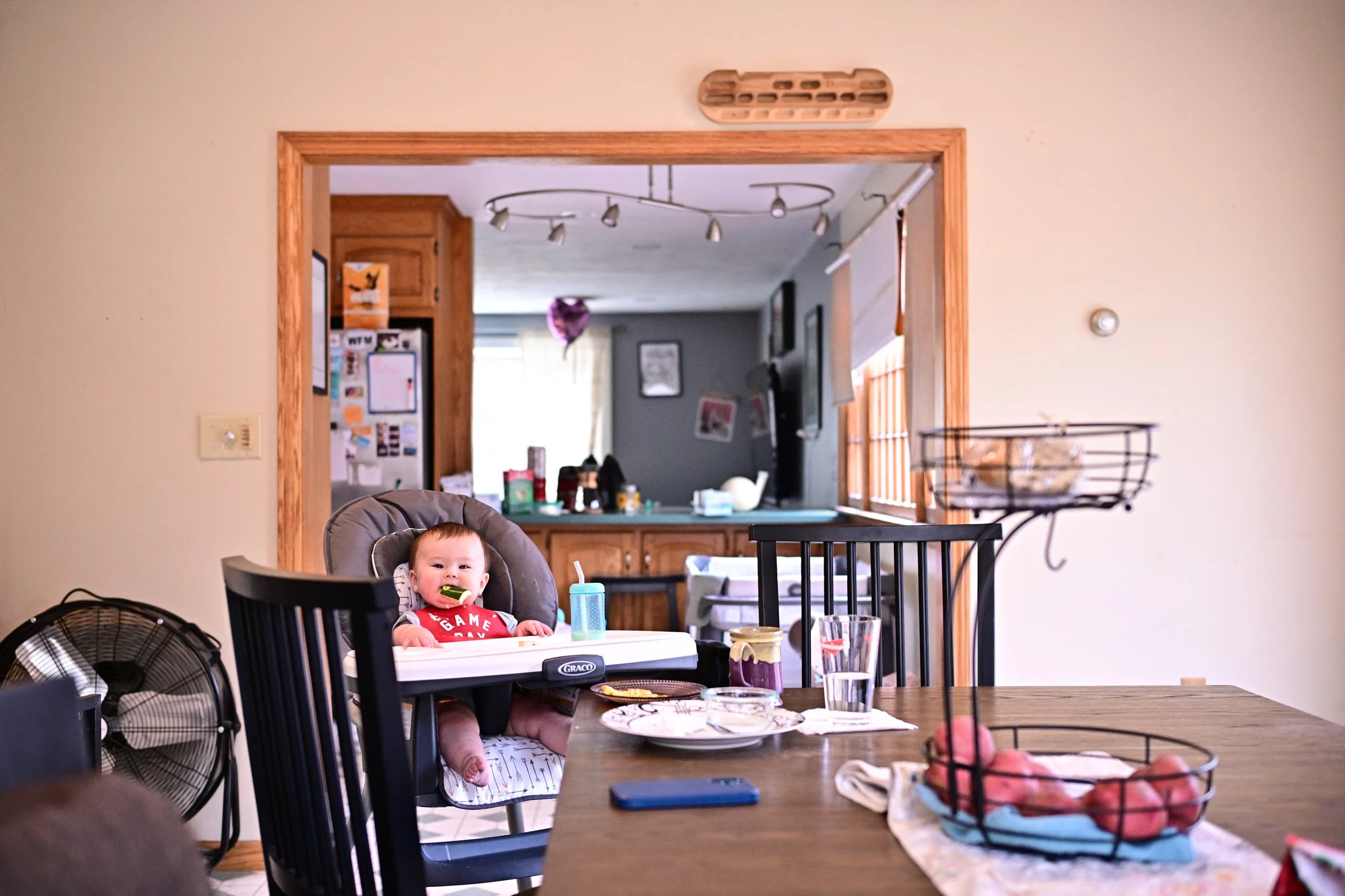 Candid baby eating breakfast in high chair, documentary in-home family photography Connecticut