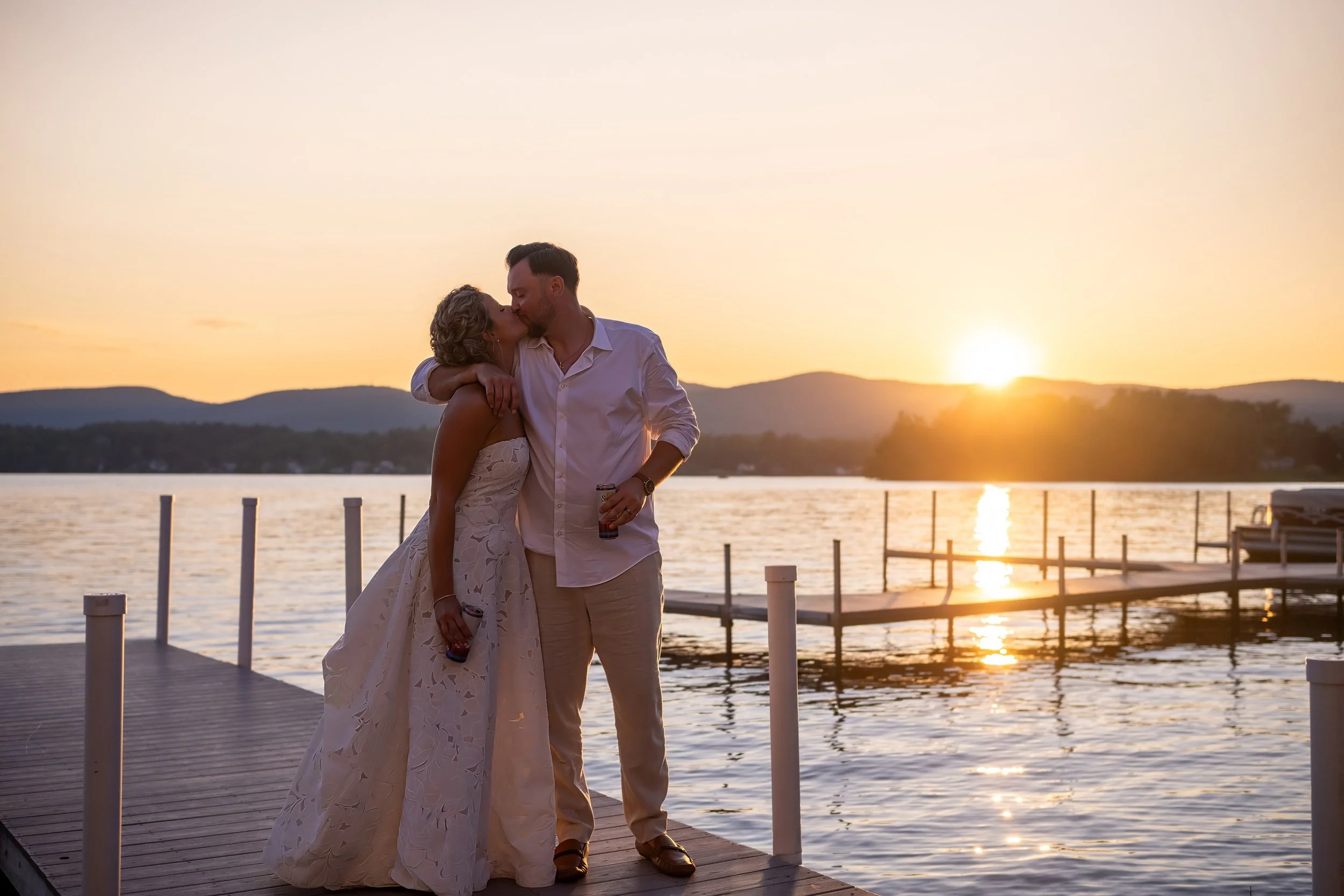Warm, golden hour wedding photo of Emily and Brandon kissing at sunset on Pontoosuc Lake, captured at The Lake House Guest Cottages of the Berkshires by Mott Collective.