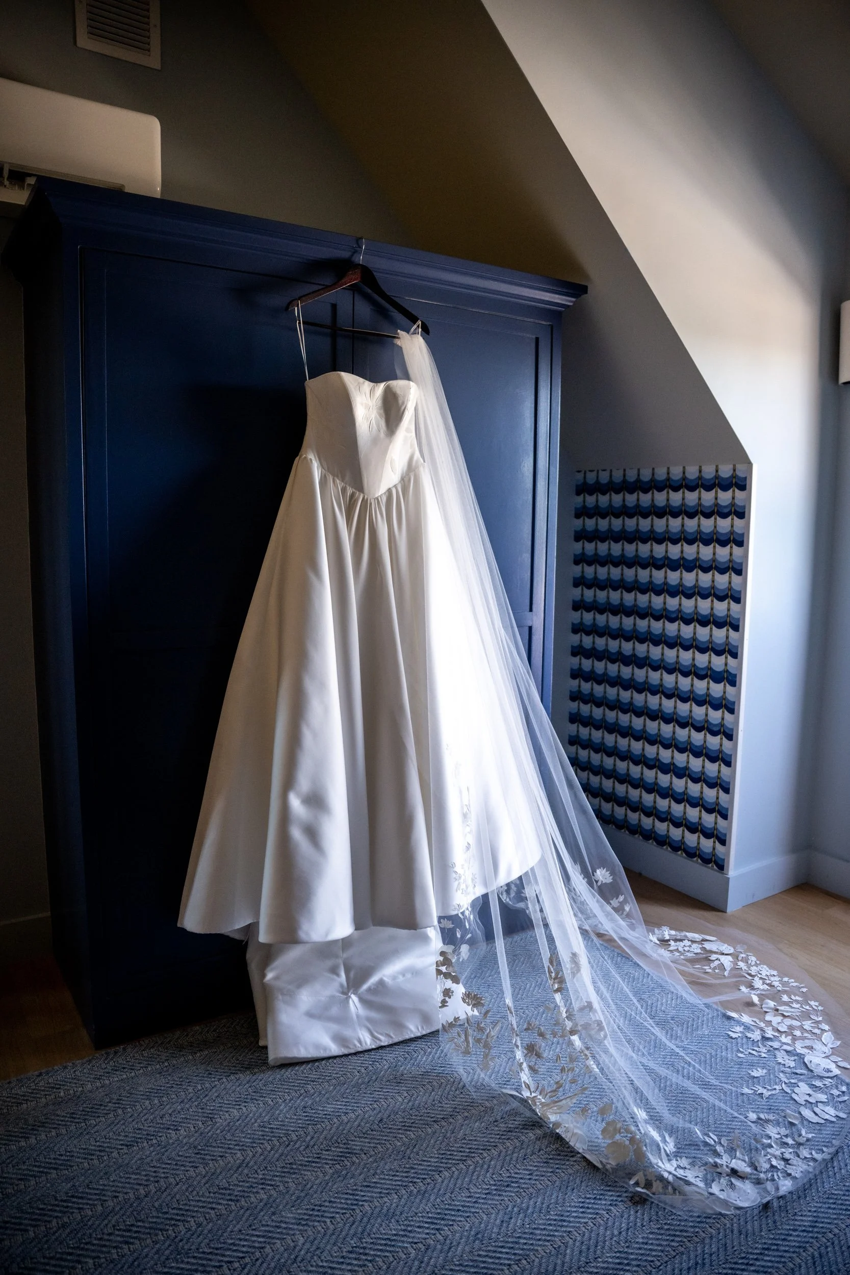 Full wedding dress hanging near a light-filled window at Delamar Mystic
