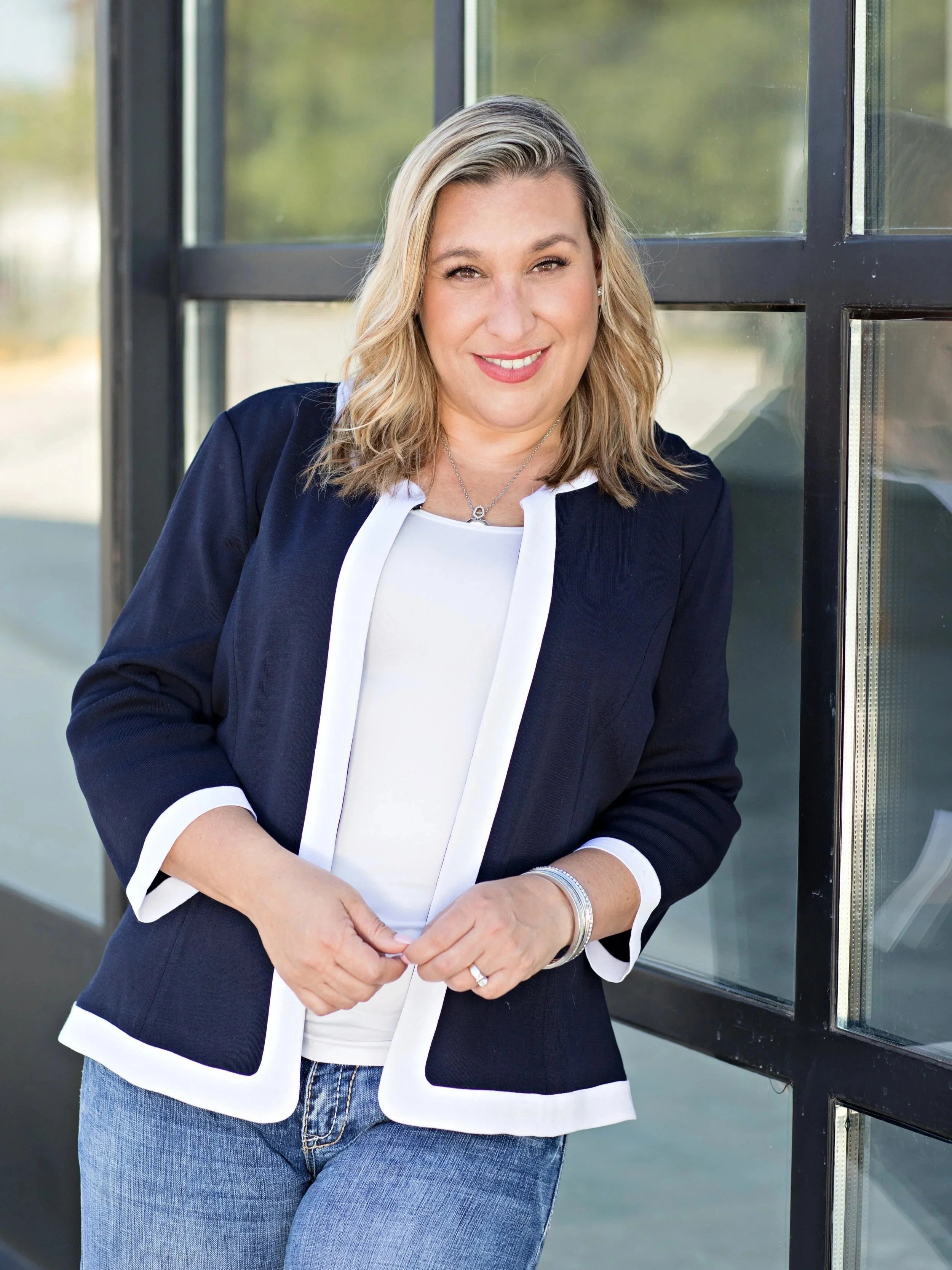 Jen Williams, founder of Lumaire Co., standing outside a building with black-framed windows