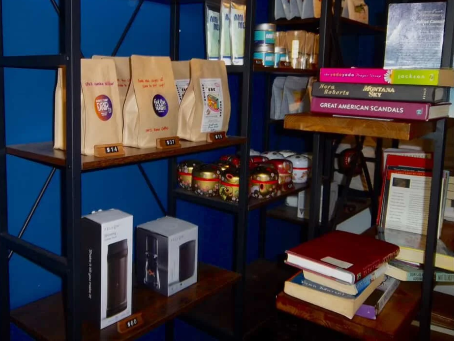 Bookshelf with coffee bags, decorative jars, books, and boxed items in a store.