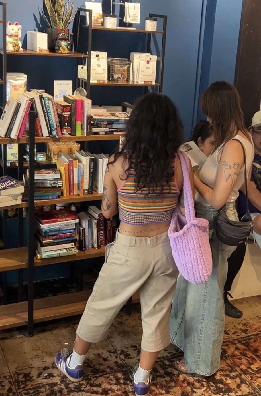 People browsing books in a bookstore, with shelves filled with books and decorative items in the background.
