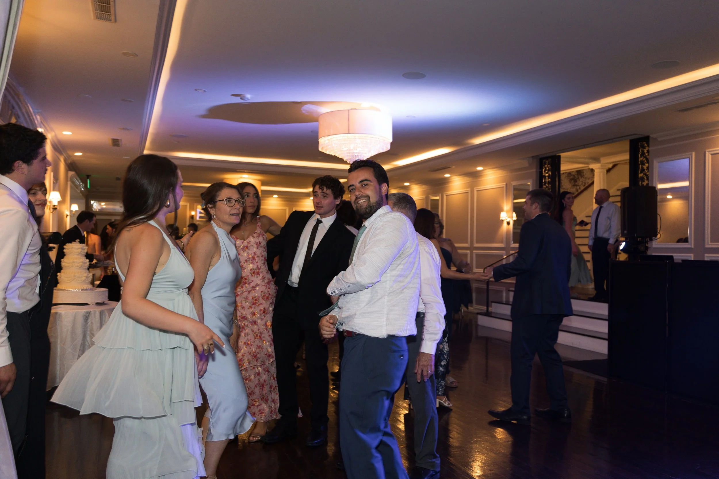 People dancing and socializing at an indoor wedding reception with elegant lighting and décor.