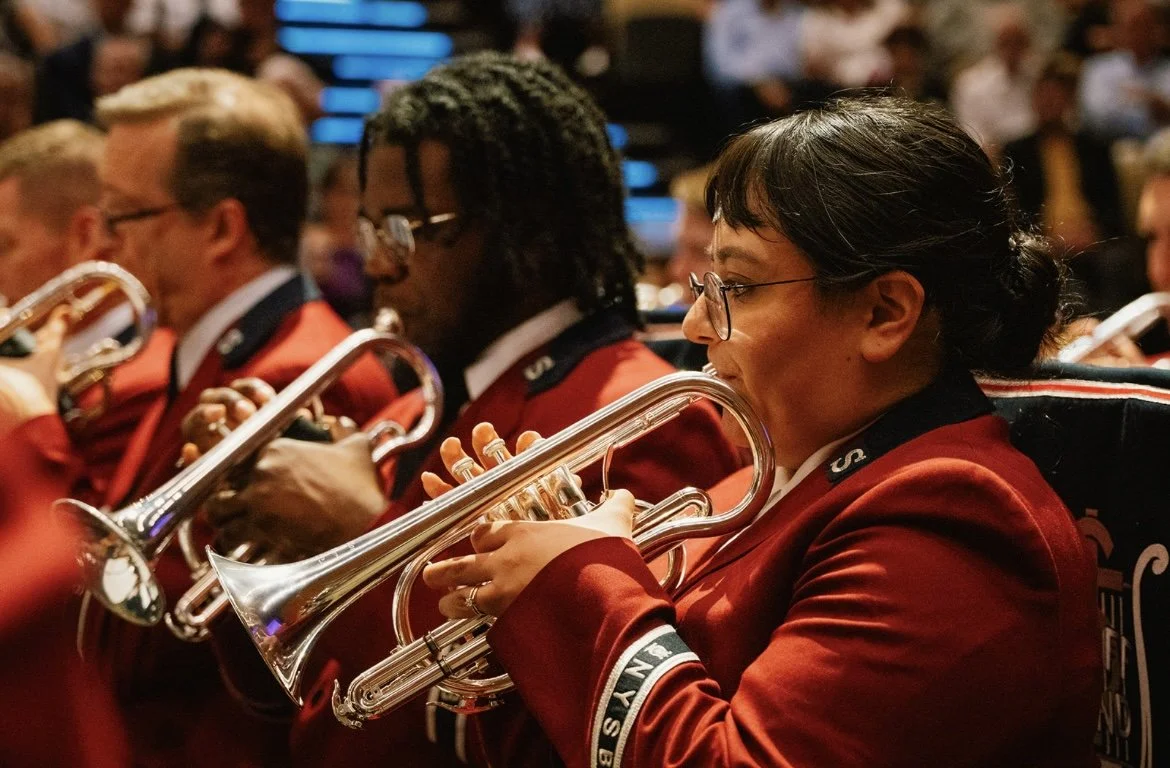 A woman in a red band uniform playing the cornet in a brass band.