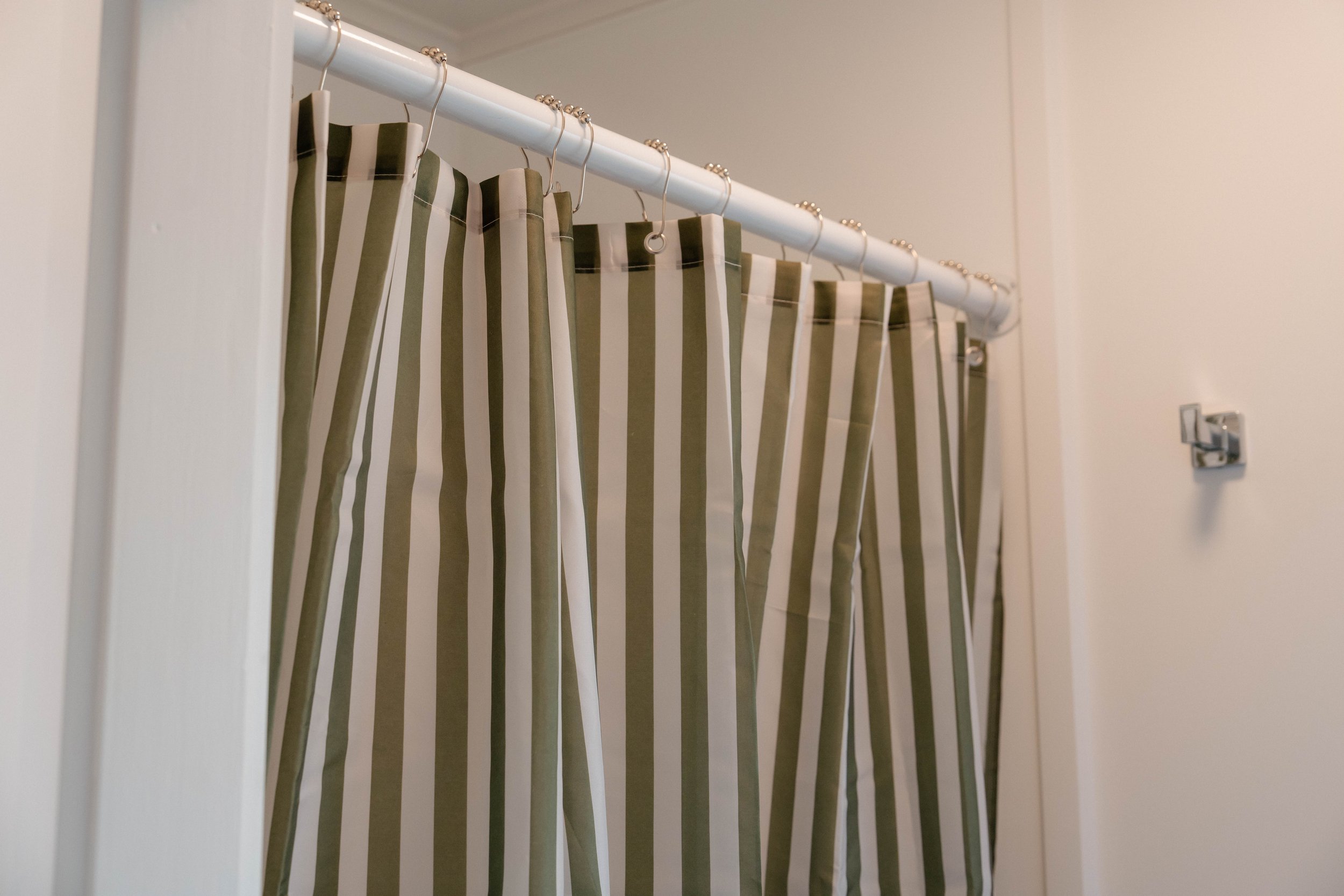 Close-up of a striped shower curtain hanging on a white shower rod in a bathroom.