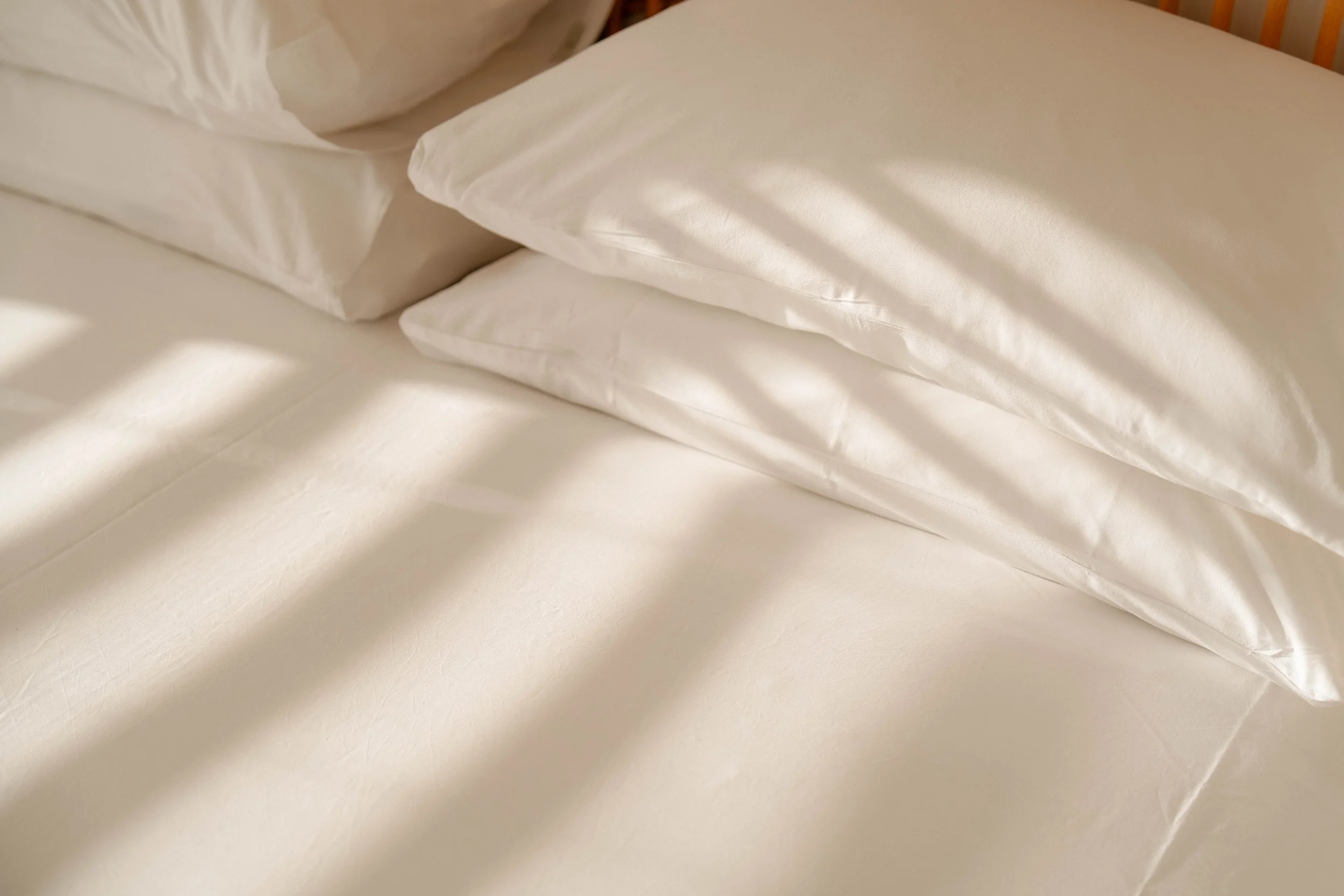 Close-up of neatly folded white bedsheets and pillows on a bed.
