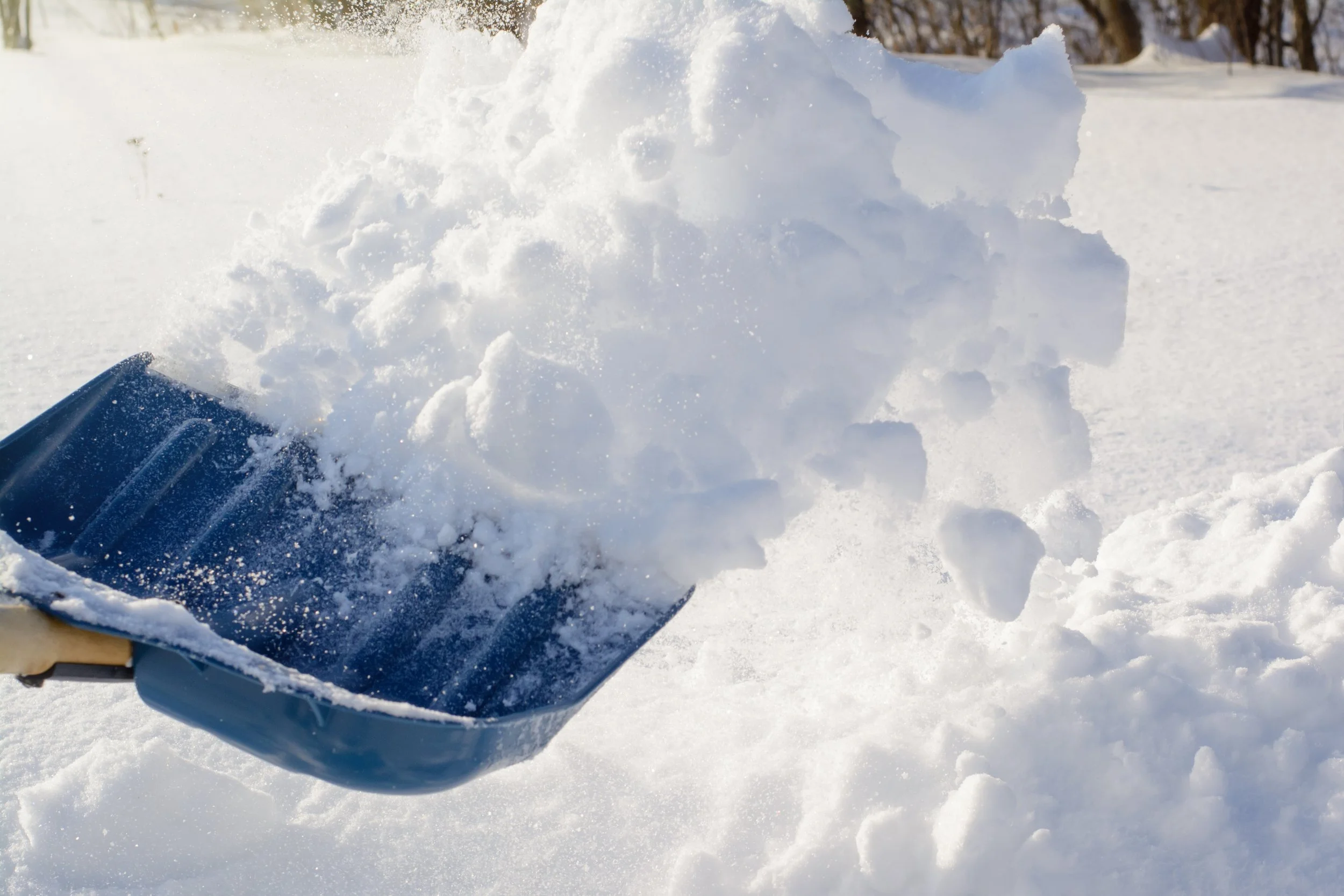 A snow shovel is scooping up snow in a snow-covered landscape.