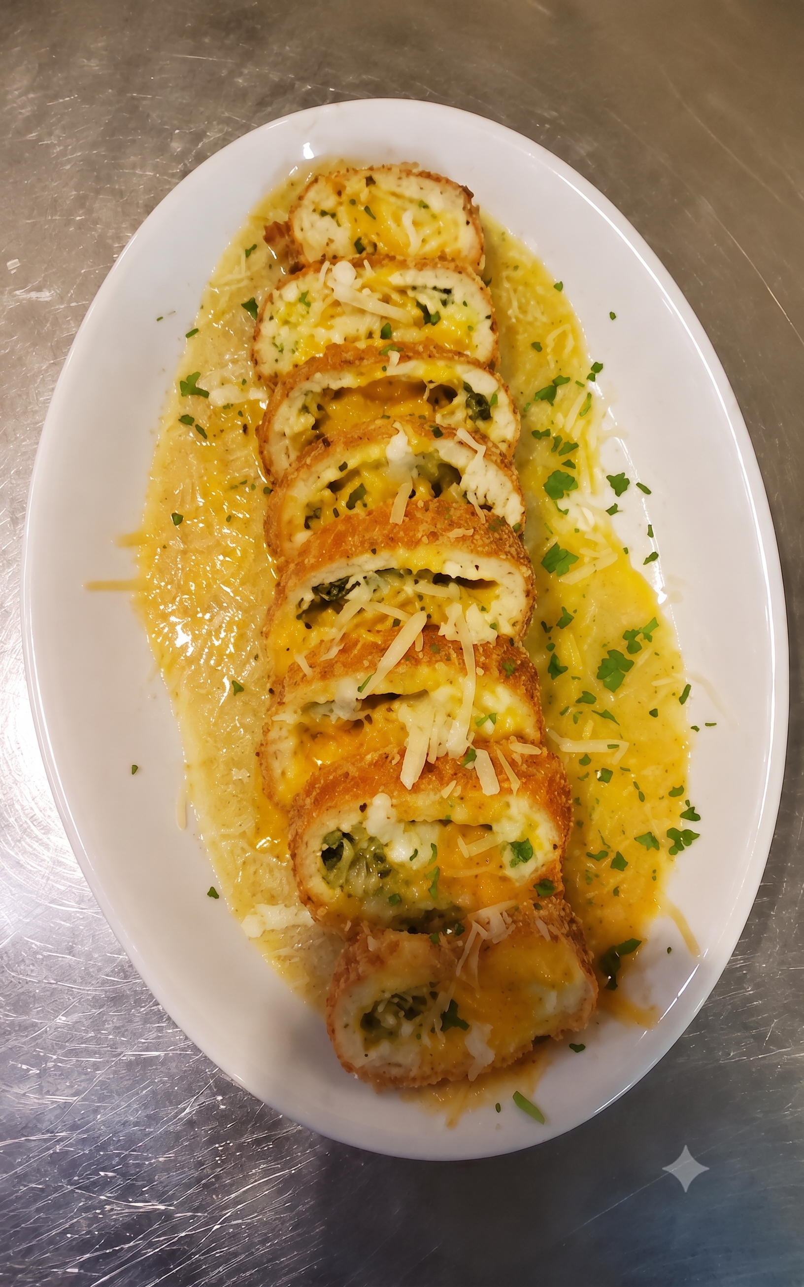 Crispy fried cheese-stuffed jalapeño poppers sliced into rounds on a white oval plate, topped with shredded cheese and chopped herbs, served with mild sauce.