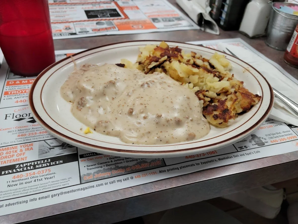 Plate of mashed potatoes with gravy and a slice of meatloaf, served on a table with newspaper advertisements underneath.