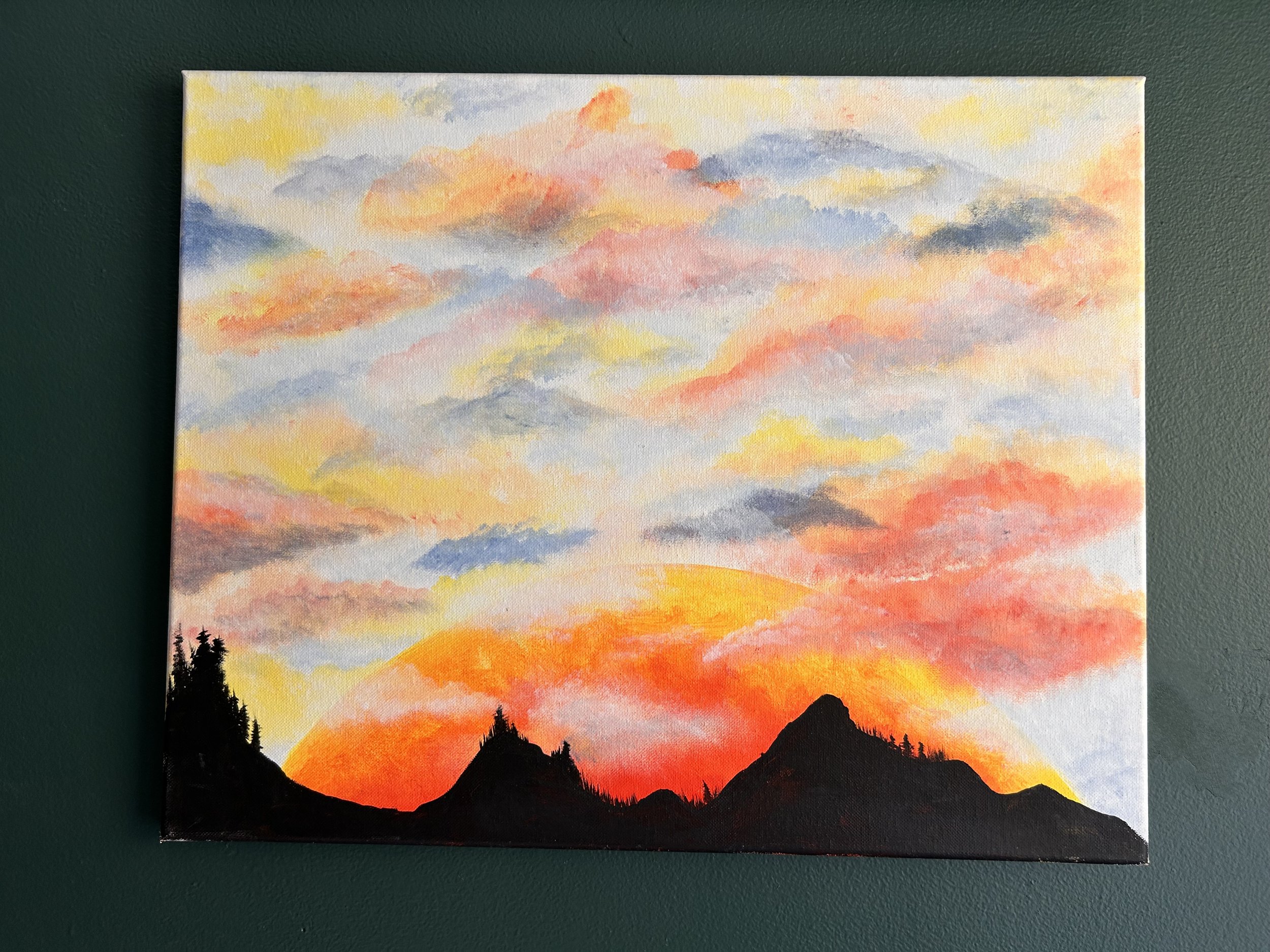 A watercolor painting of a sunset with a colorful sky, silhouetted mountains, and trees in the foreground.