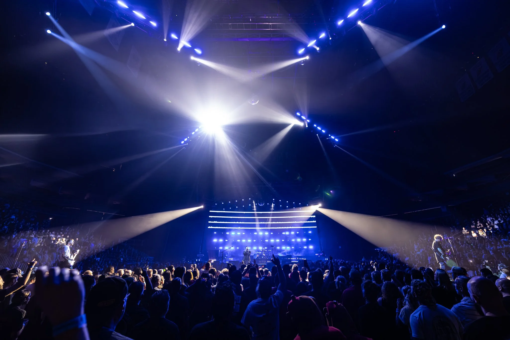A concert or show with bright stage lights shining down on an audience in a dark venue