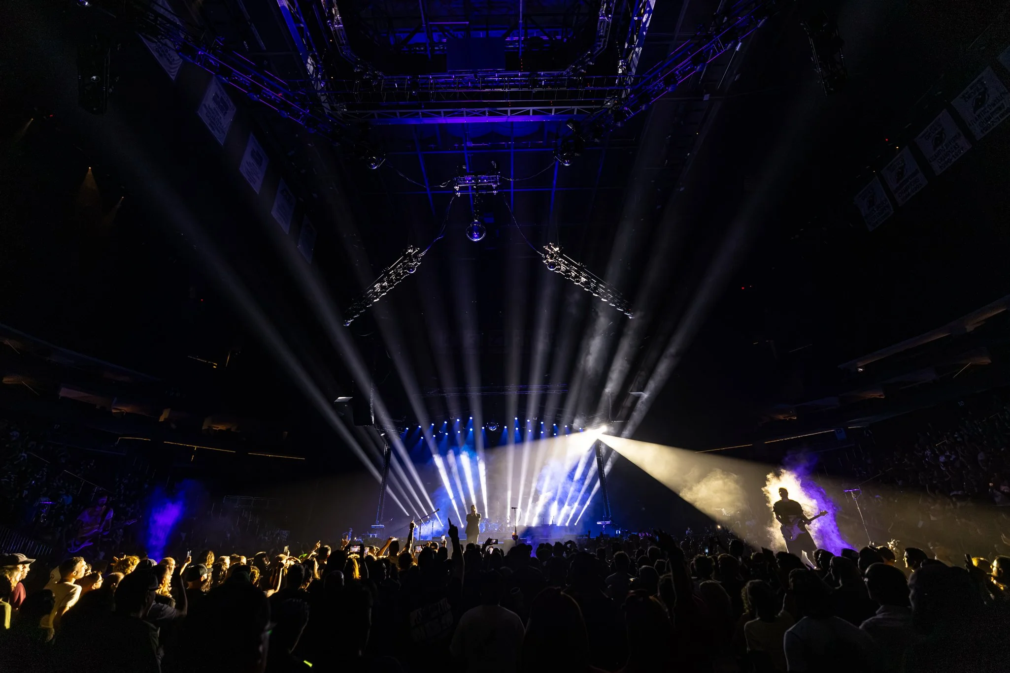 A concert scene with bright stage lights shining down on the audience and performers, creating a vibrant atmosphere in an indoor concert hall.