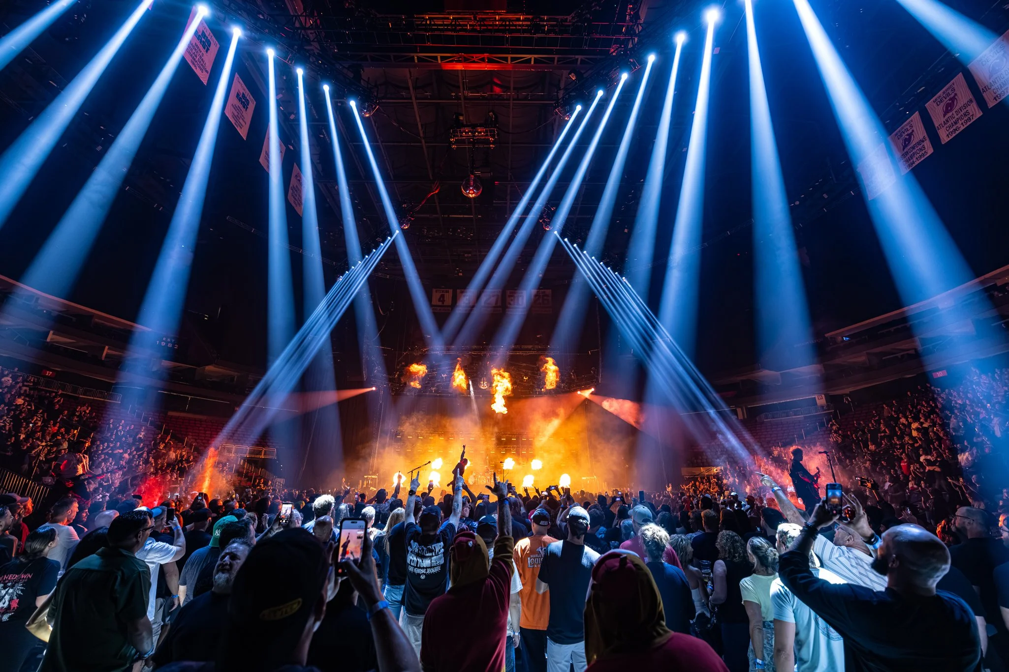 Crowd at a concert or music event with stage lighting and pyrotechnics.
