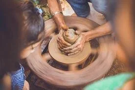 People making pottery on a spinning pottery wheel.