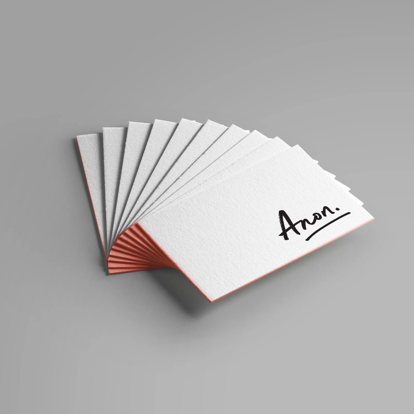 A white paper fan with the name 'Ana' written in black on it, fanned out on a gray surface.