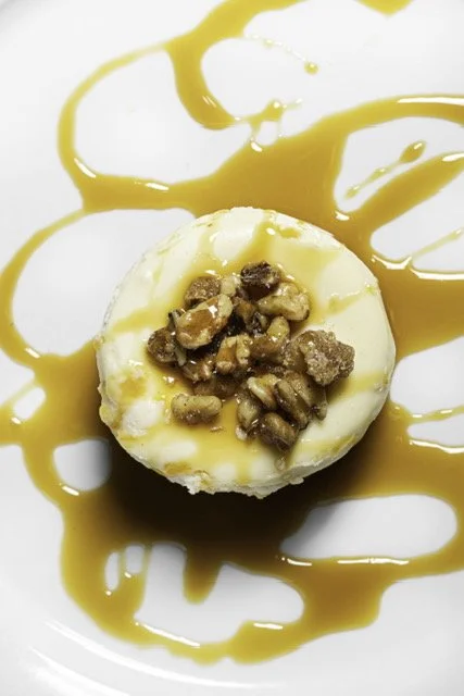 Ice cream scoop topped with caramel and chopped nuts, drizzled with caramel sauce.