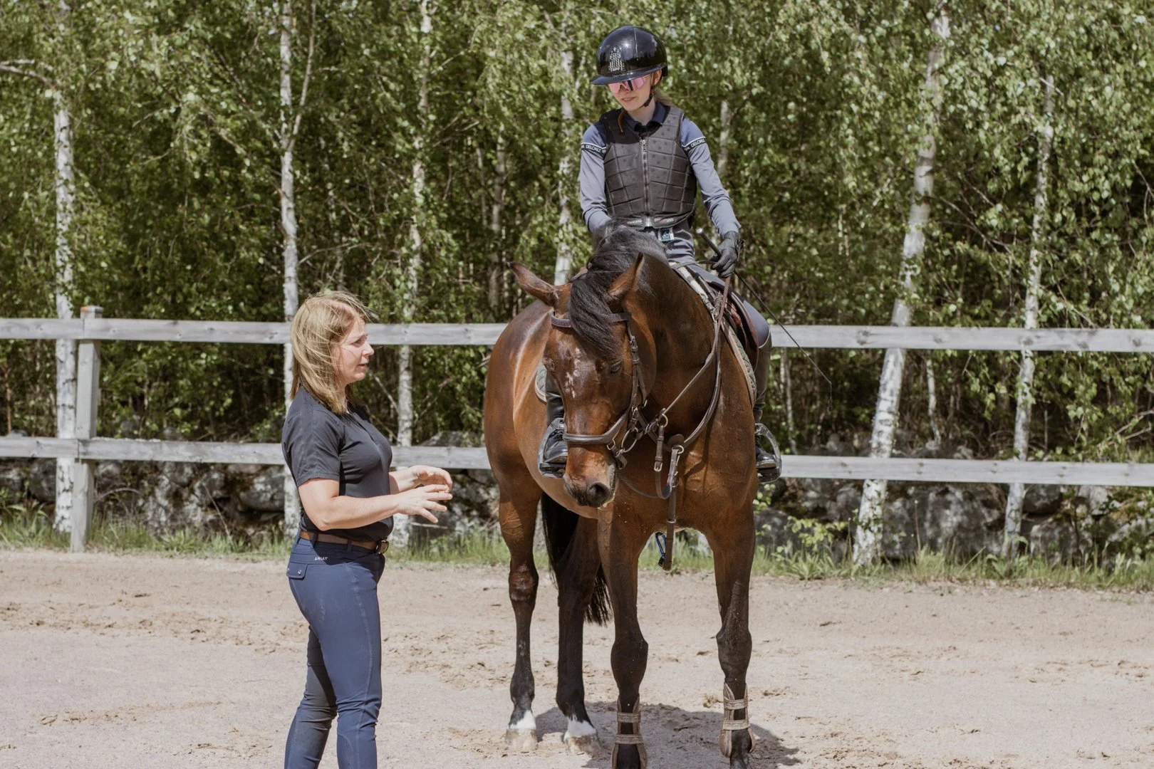 Hopptränare som förklarar för elev som sitter på en häst