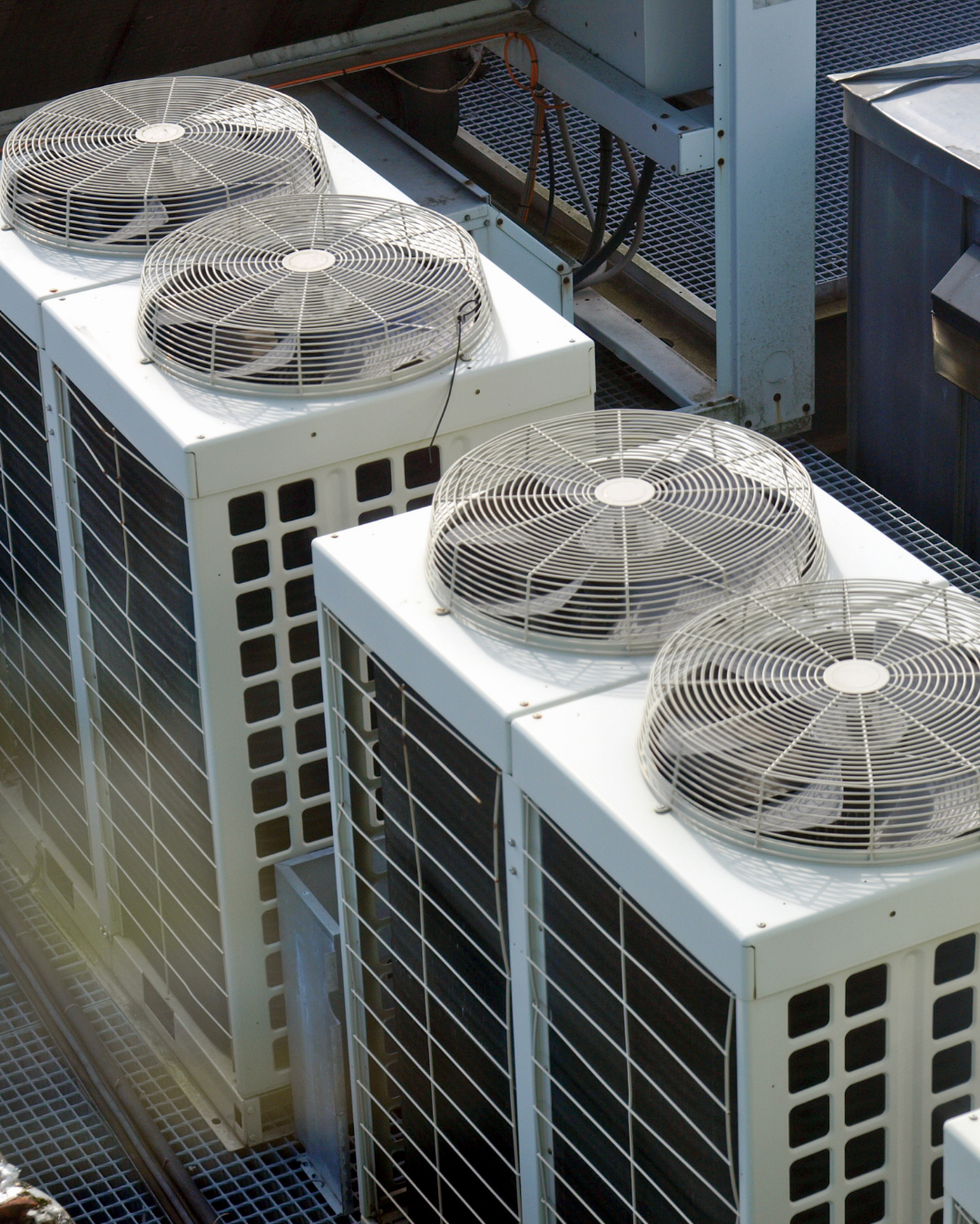 Un conjunto de unidades de aire acondicionado con ventiladores en la parte superior instaladas en un techo industrial.
