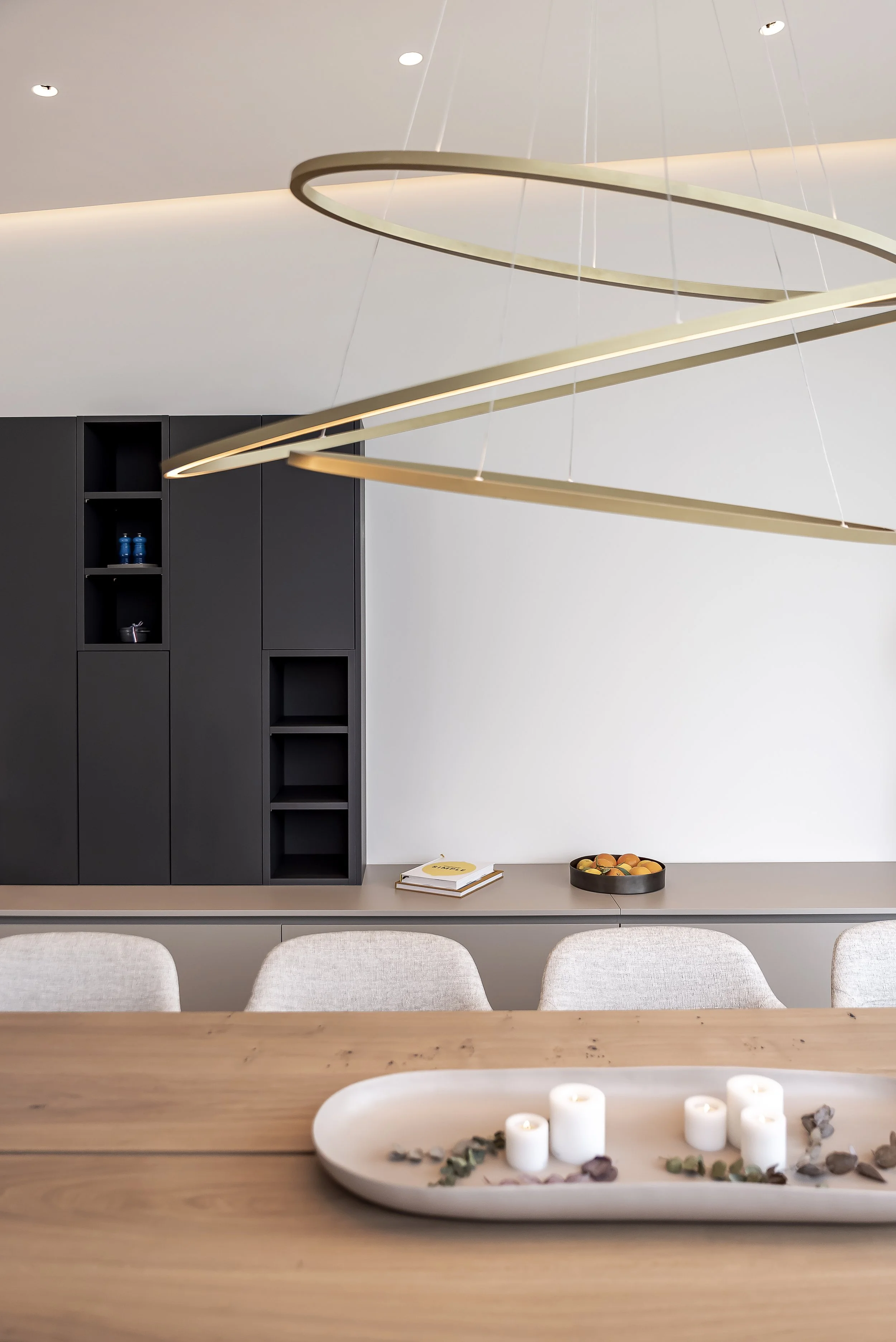 Interiores modernos con mesa de madera, adornos blancos, velas y construcción minimalista en tonos neutrales.
