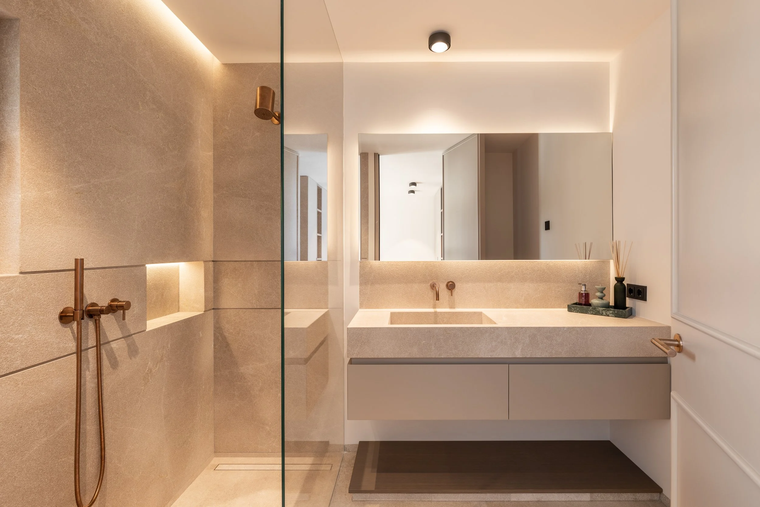 Un baño moderno con lavabo de piedra, espejo grande y decoración minimalista.