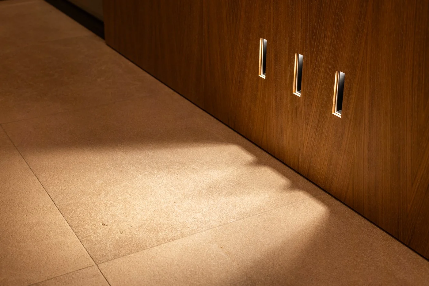 Suelo de baldosas beige frente a una pared de madera con ranuras para bolsos.
