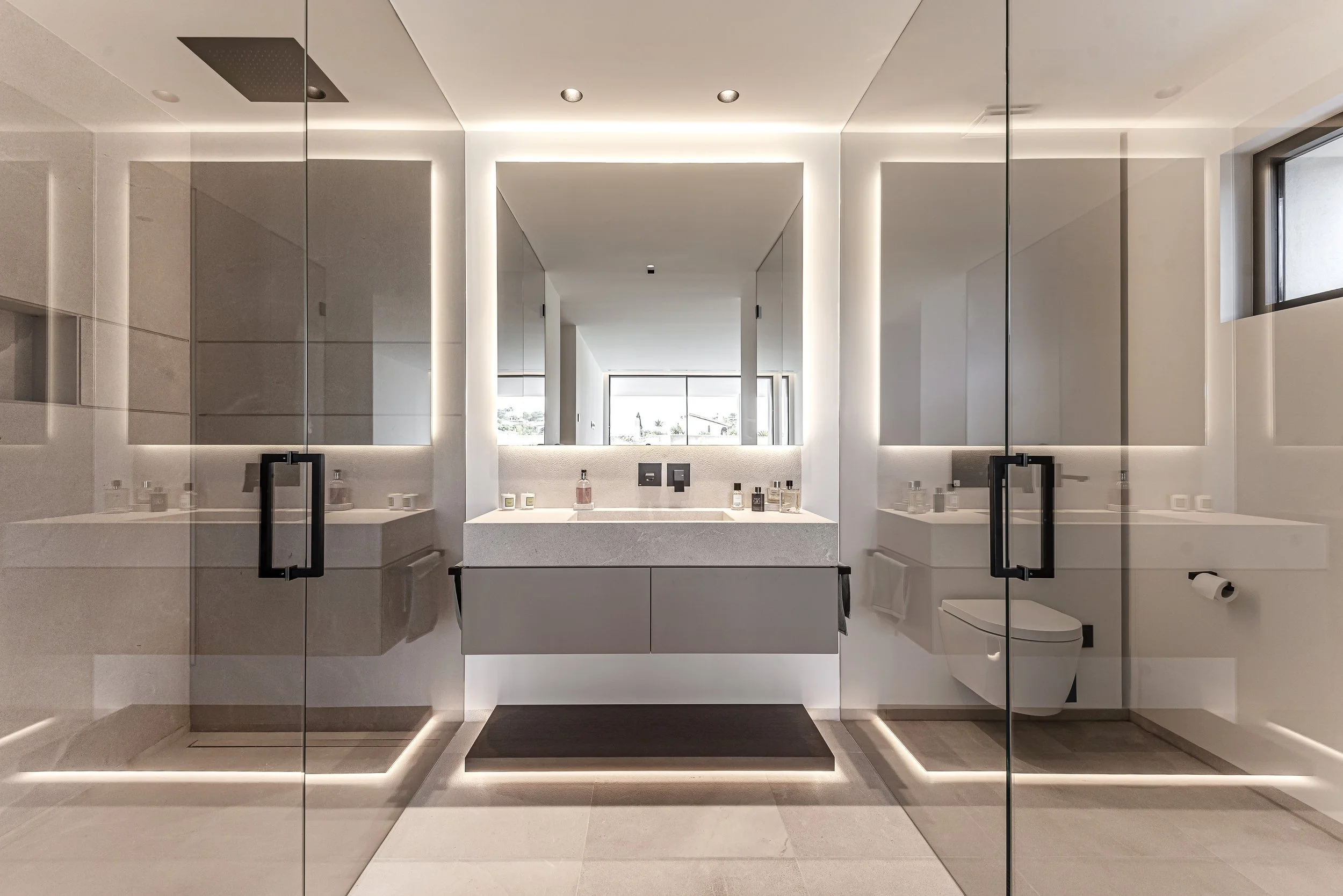 Baño moderno con espejo grande, lavabo, y ducha con puertas de vidrio.